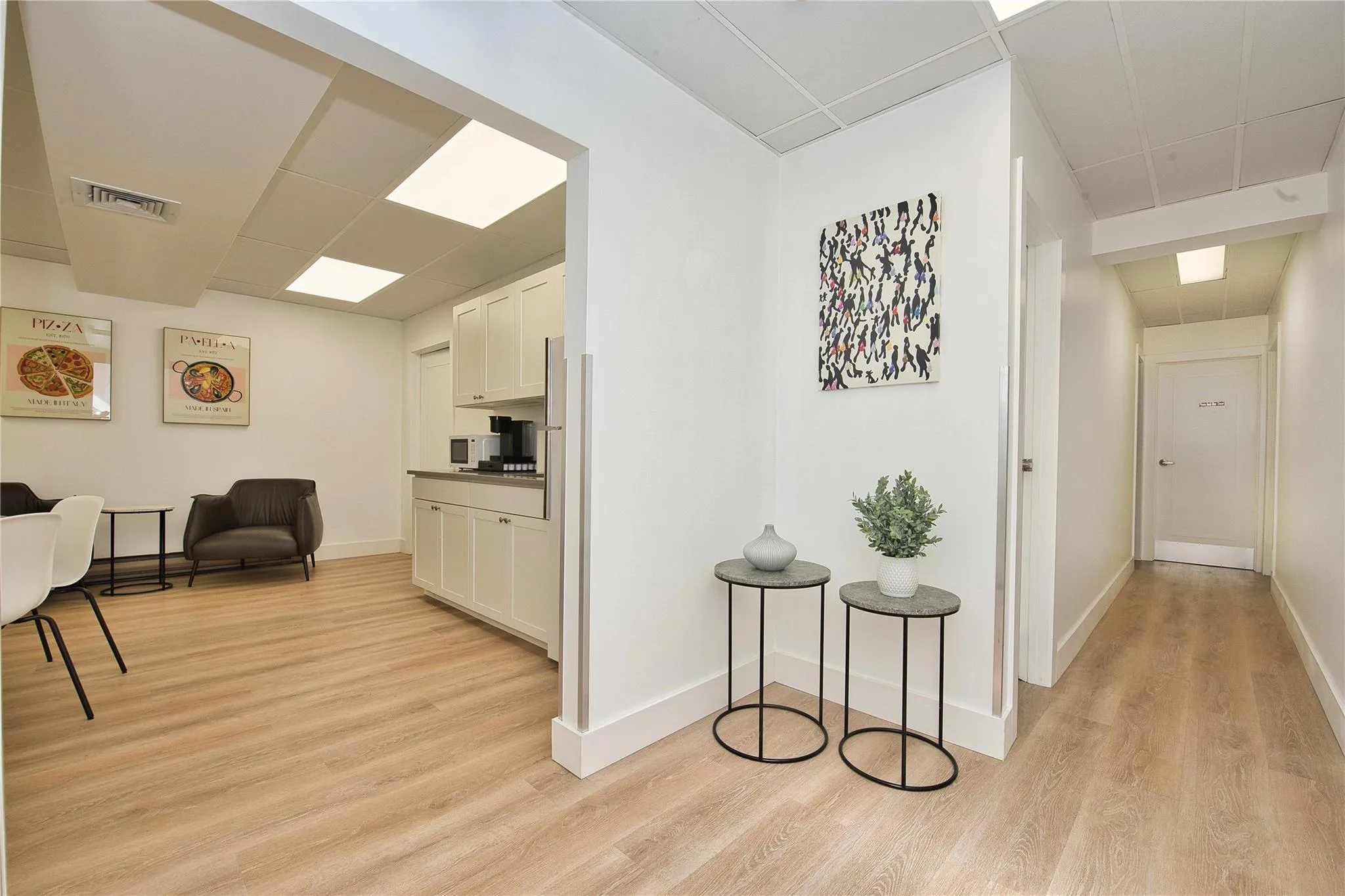 Hall featuring light wood-style floors, baseboards, and a drop ceiling Hall featuring light wood-style floors, baseboards, and a drop ceiling