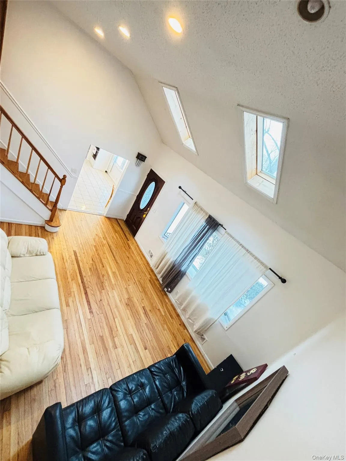 Living area featuring a textured ceiling, hardwood / wood-style flooring, stairs, high vaulted ceiling, and recessed lighting Living area featuring a textured ceiling, hardwood / wood-style flooring, stairs, high vaulted ceiling, and recessed lighting