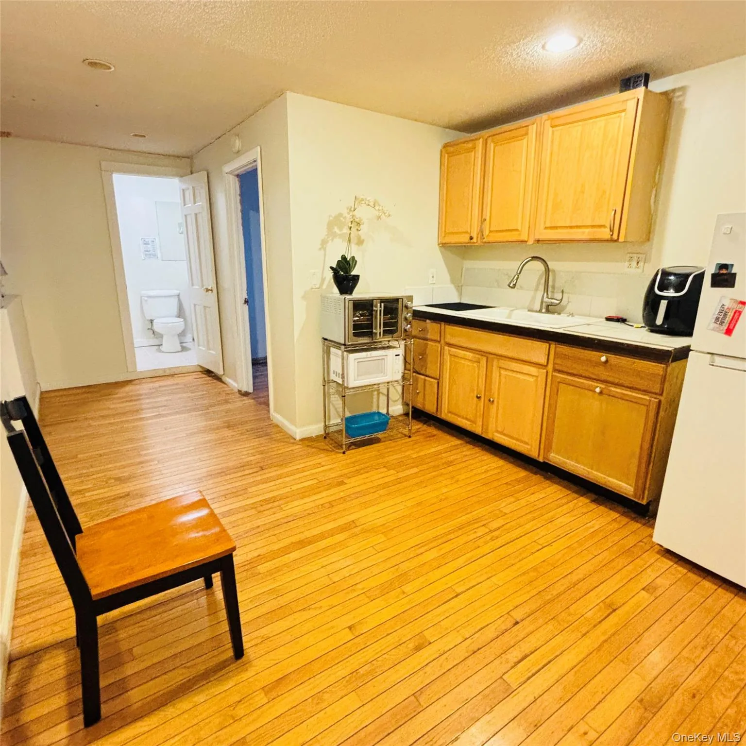 Kitchen with a textured ceiling, freestanding refrigerator, and light wood finished floors Kitchen with a textured ceiling, freestanding refrigerator, and light wood finished floors