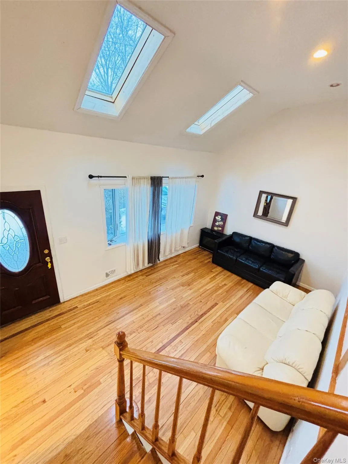 Living room featuring vaulted ceiling, a bow window two skylights, light wood finished floors, and recessed lighting Living room featuring vaulted ceiling, a bow window two skylights, light wood finished floors, and recessed lighting