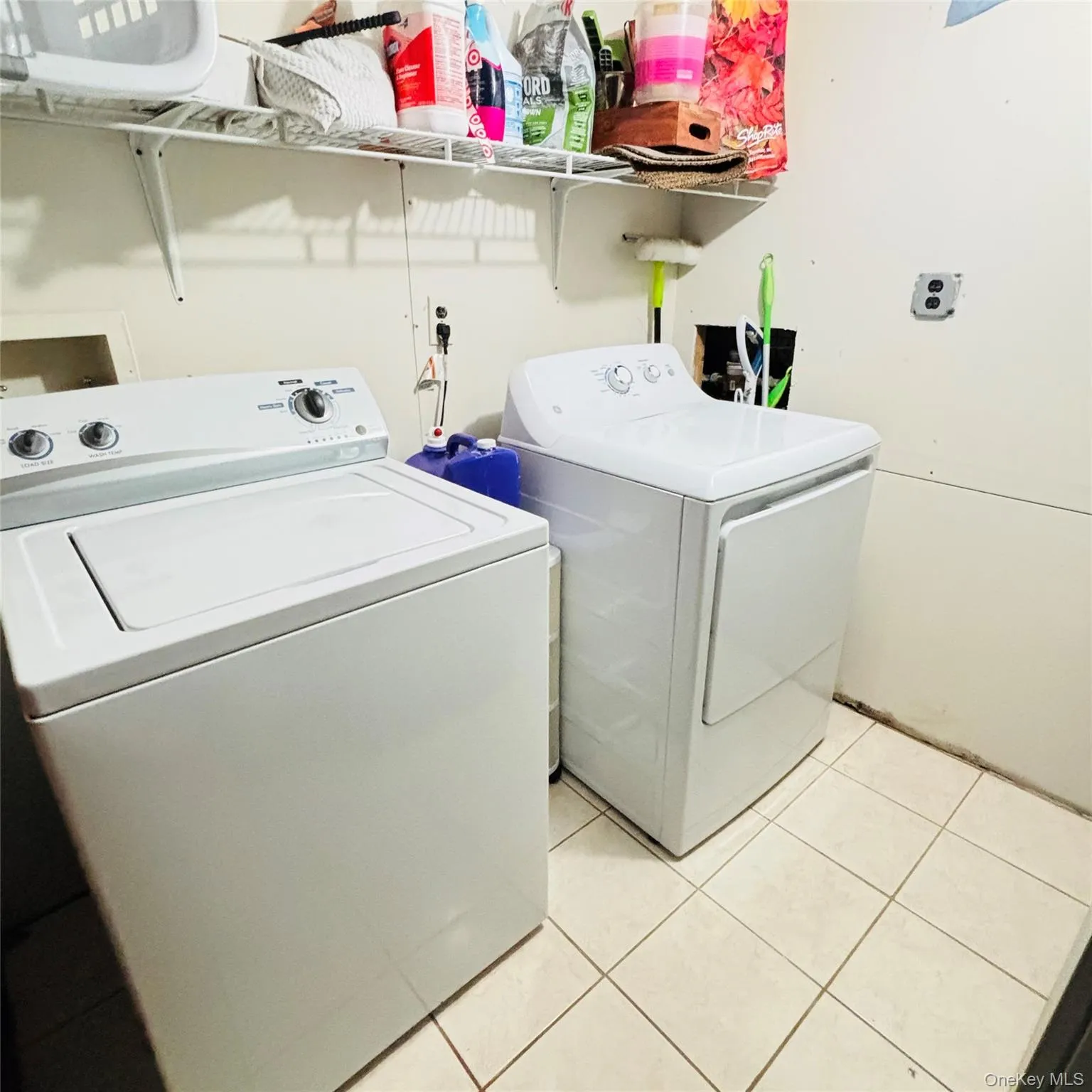 Laundry area with washing machine and clothes dryer and light tile patterned floors Laundry area with washing machine and clothes dryer and light tile patterned floors
