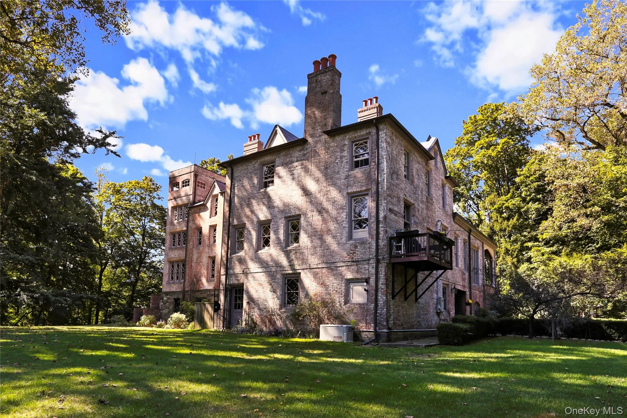 Back of house with a lawn, a chimney, brick siding, and a balcony Back of house with a lawn, a chimney, brick siding, and a balcony