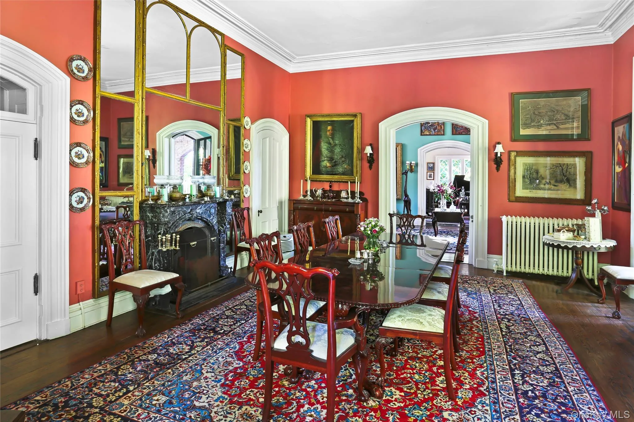 Dining space featuring radiator heating unit, wood finished floors, a fireplace, arched walkways, and crown molding Dining space featuring radiator heating unit, wood finished floors, a fireplace, arched walkways, and crown molding