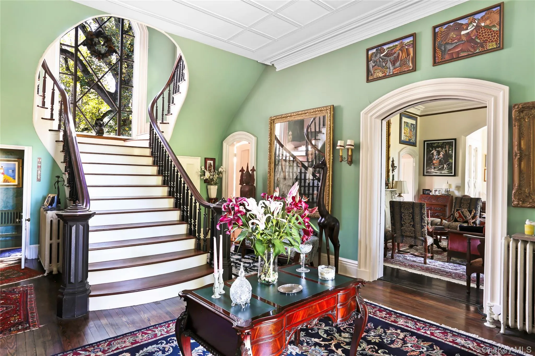 Stairway featuring radiator, hardwood / wood-style floors, arched walkways, baseboards, and ornamental molding Stairway featuring radiator, hardwood / wood-style floors, arched walkways, baseboards, and ornamental molding