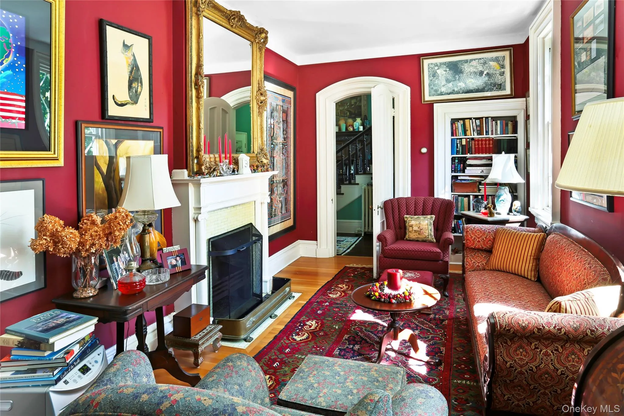 Living room with wood finished floors, a fireplace, arched walkways, and baseboards Living room with wood finished floors, a fireplace, arched walkways, and baseboards