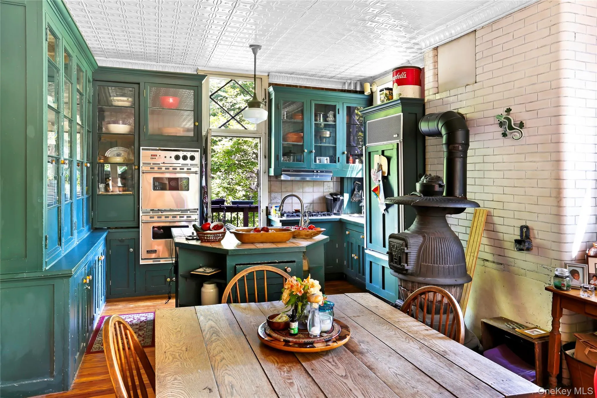 Dining space with an ornate ceiling, light wood finished floors, brick wall, crown molding, and a wood stove Dining space with an ornate ceiling, light wood finished floors, brick wall, crown molding, and a wood stove