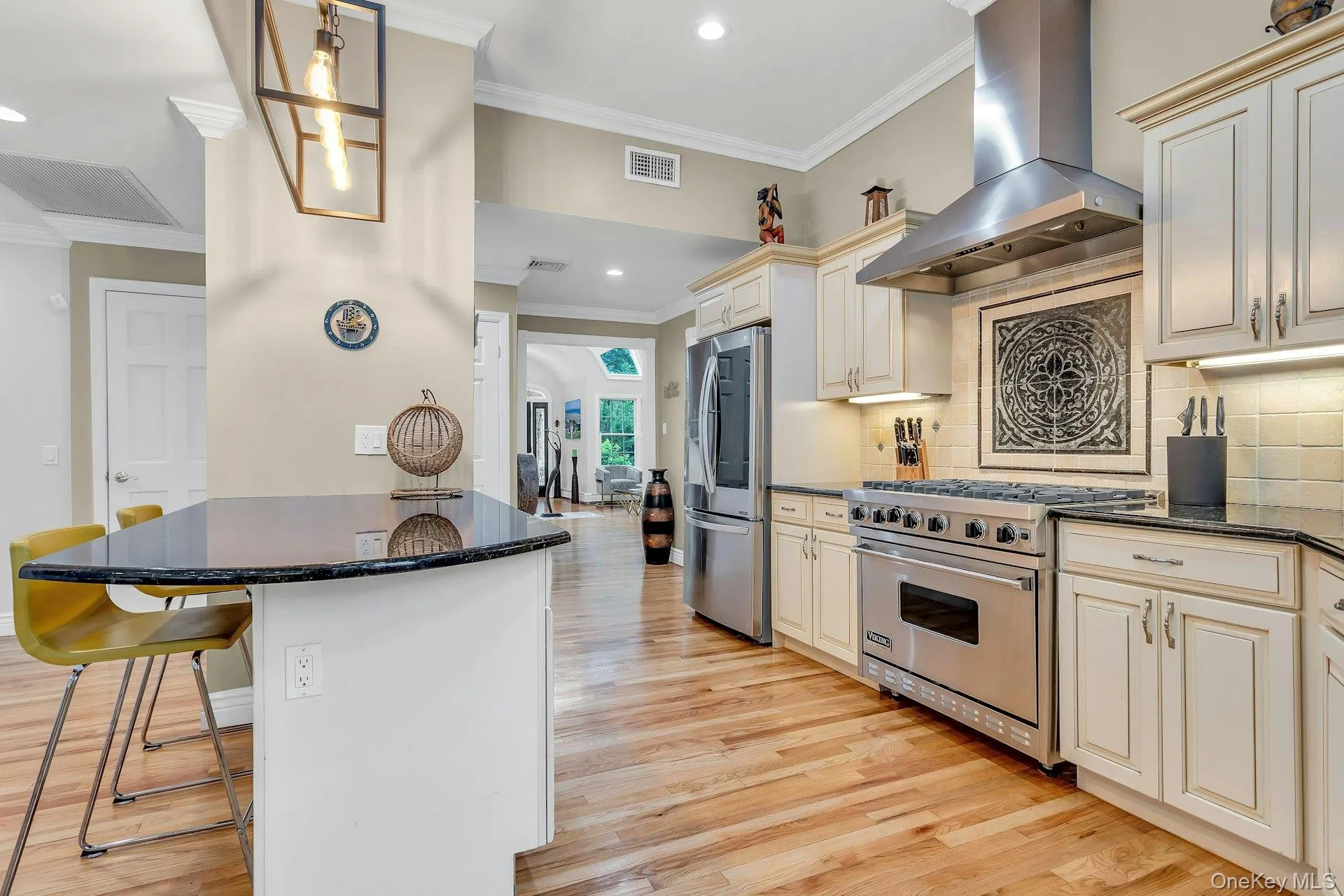 Kitchen with exhaust hood, stainless steel appliances, crown molding, cream cabinets, and a breakfast bar Kitchen with exhaust hood, stainless steel appliances, crown molding, cream cabinets, and a breakfast bar