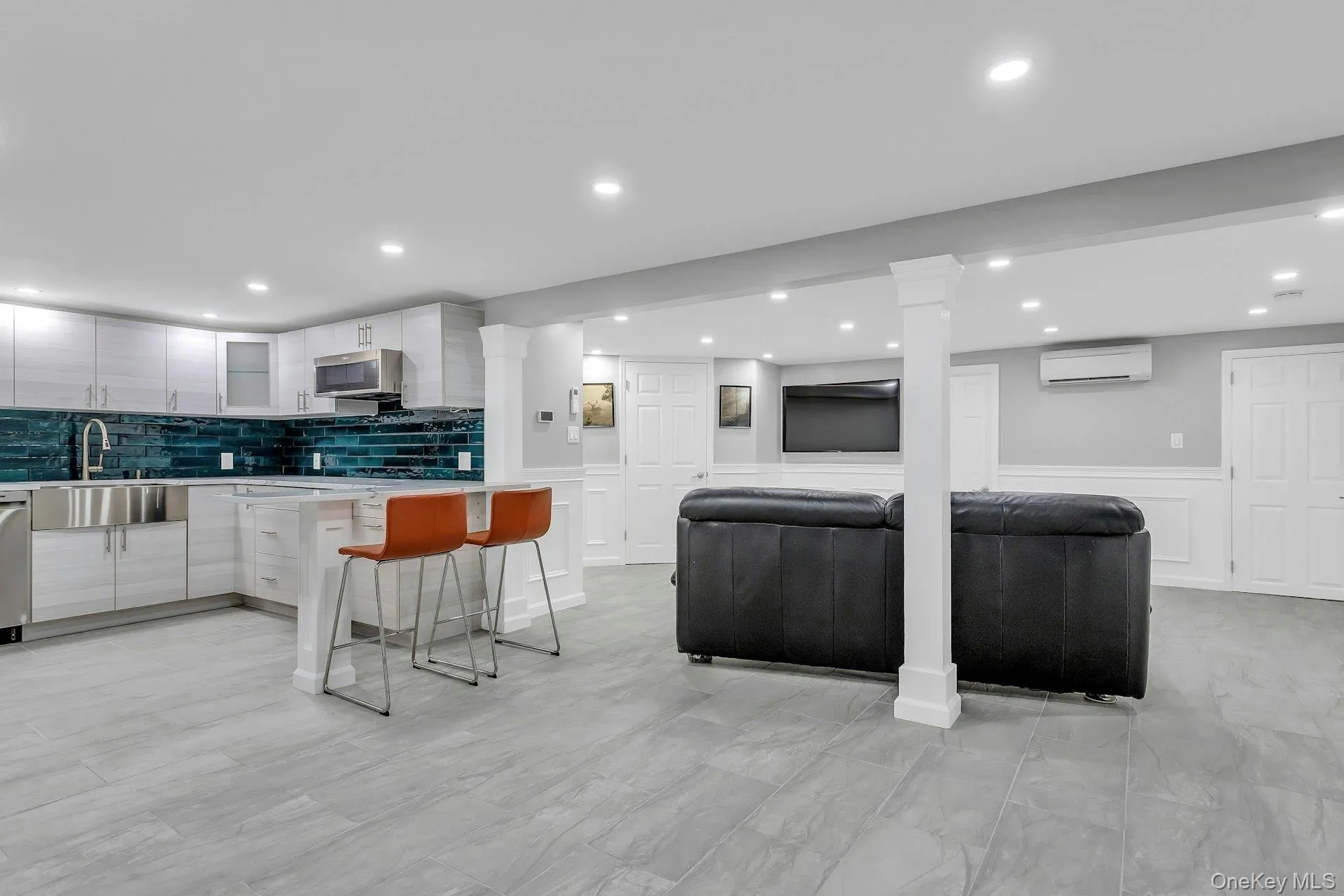 Kitchen featuring a sink, a wall unit AC, appliances with stainless steel finishes, light countertops, and modern cabinets Kitchen featuring a sink, a wall unit AC, appliances with stainless steel finishes, light countertops, and modern cabinets