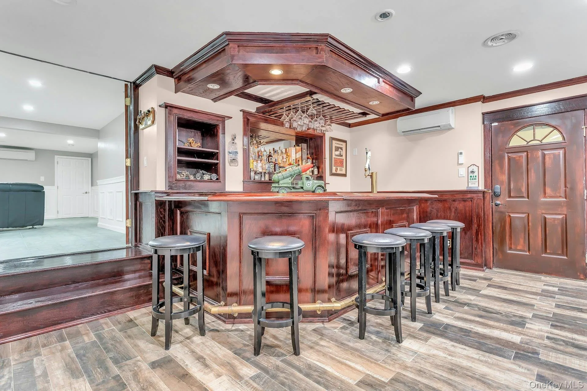 Indoor wet bar featuring a wall unit AC, a wainscoted wall, wood finished floors, a decorative wall, and ornamental molding Indoor wet bar featuring a wall unit AC, a wainscoted wall, wood finished floors, a decorative wall, and ornamental molding