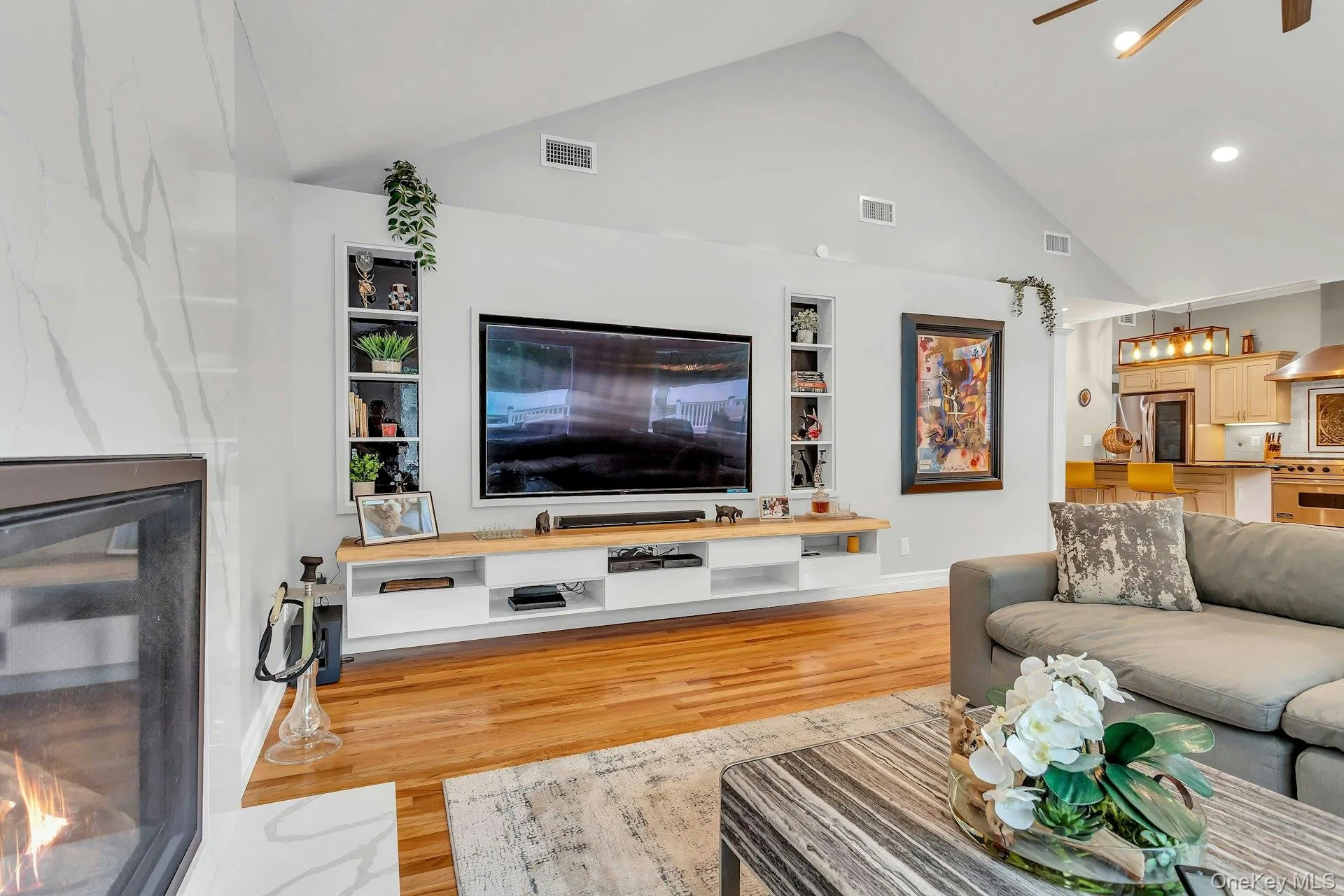 Living area with built in features, wood finished floors, recessed lighting, high vaulted ceiling, and baseboards Living area with built in features, wood finished floors, recessed lighting, high vaulted ceiling, and baseboards