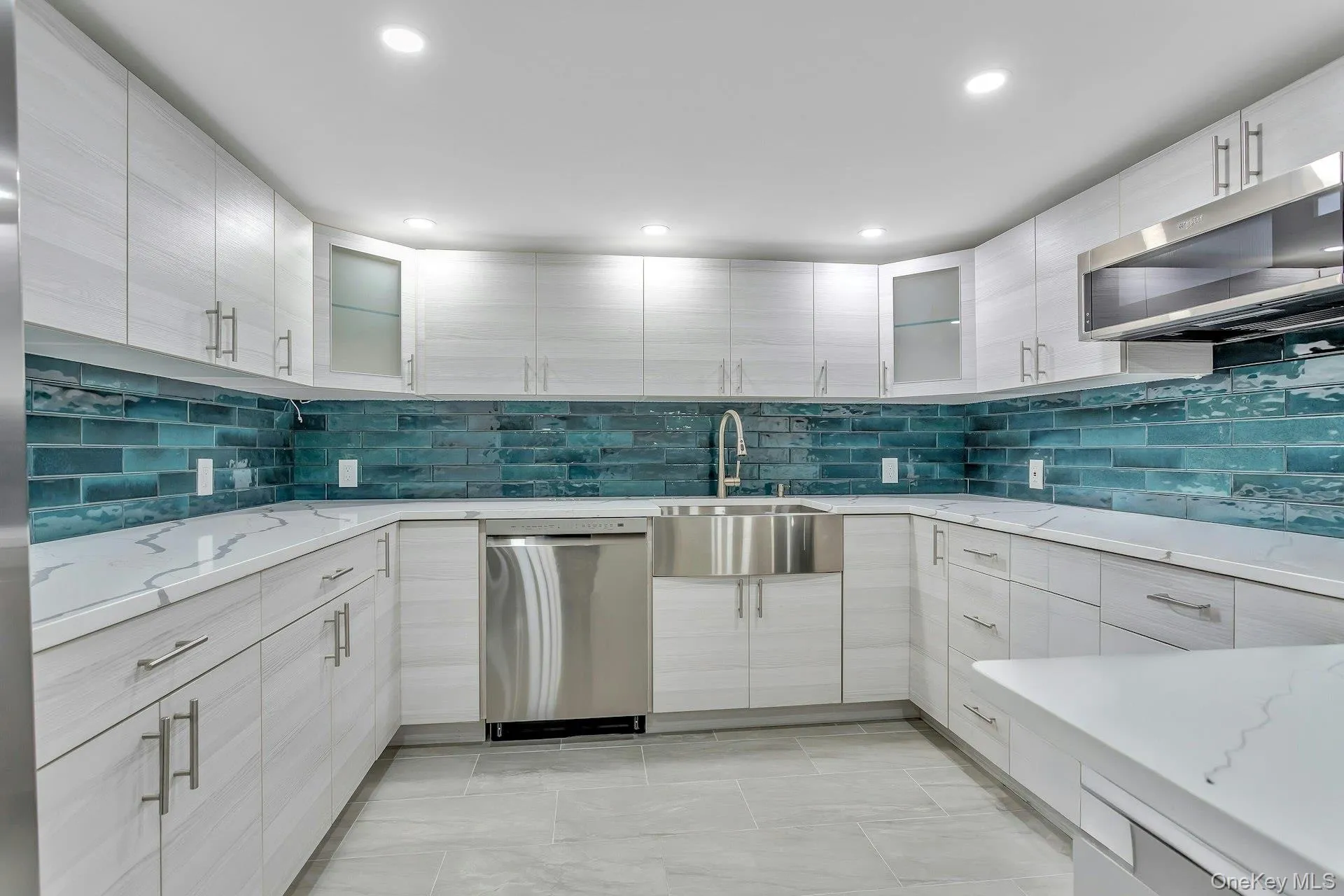 Kitchen with appliances with stainless steel finishes, a sink, tasteful backsplash, glass insert cabinets, and recessed lighting Kitchen with appliances with stainless steel finishes, a sink, tasteful backsplash, glass insert cabinets, and recessed lighting