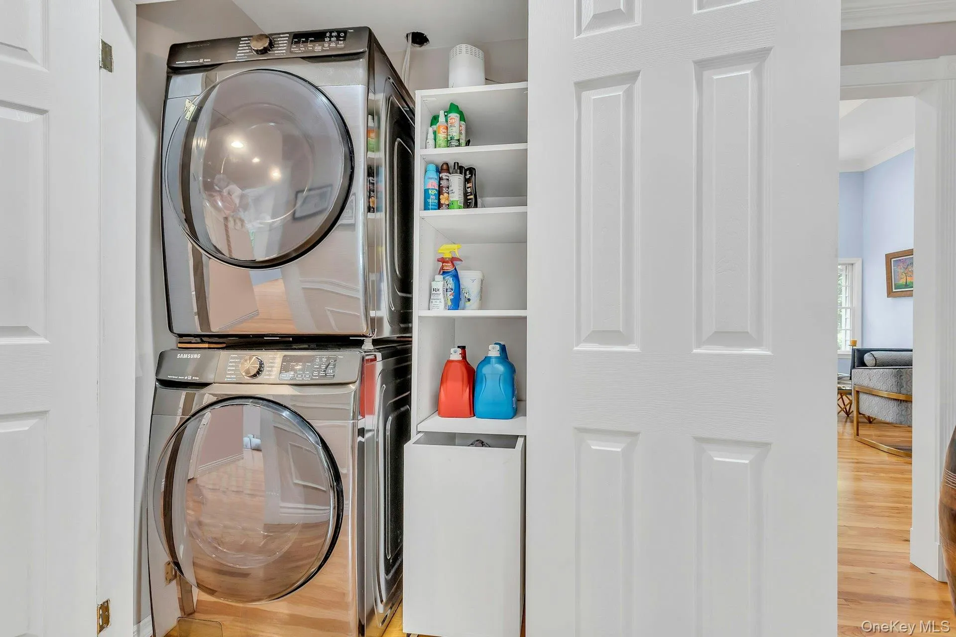 Laundry room with stacked washer and clothes dryer, wood finished floors, and crown molding Laundry room with stacked washer and clothes dryer, wood finished floors, and crown molding