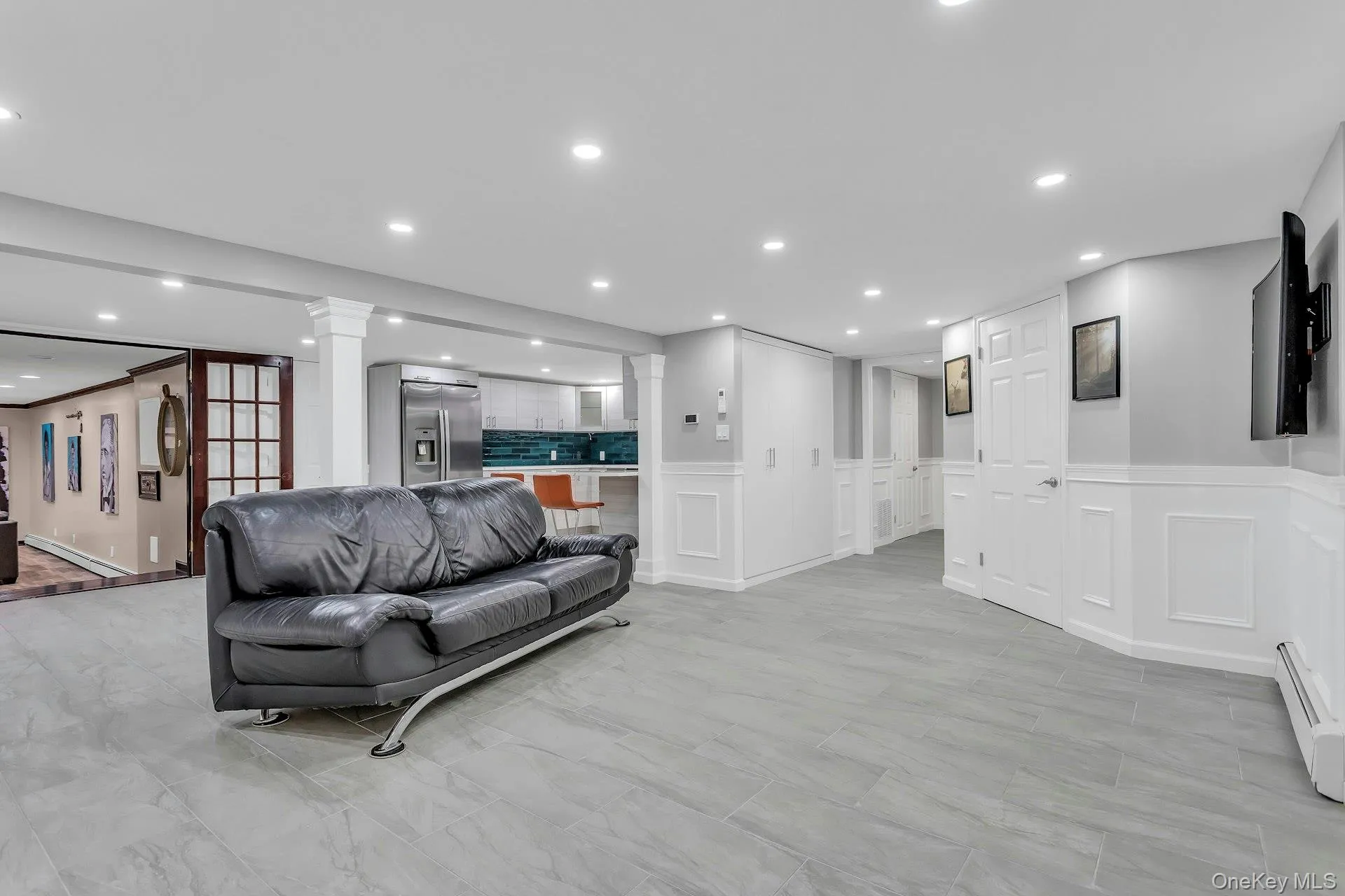Living room with decorative columns, a decorative wall, recessed lighting, wainscoting, and a baseboard heating unit Living room with decorative columns, a decorative wall, recessed lighting, wainscoting, and a baseboard heating unit