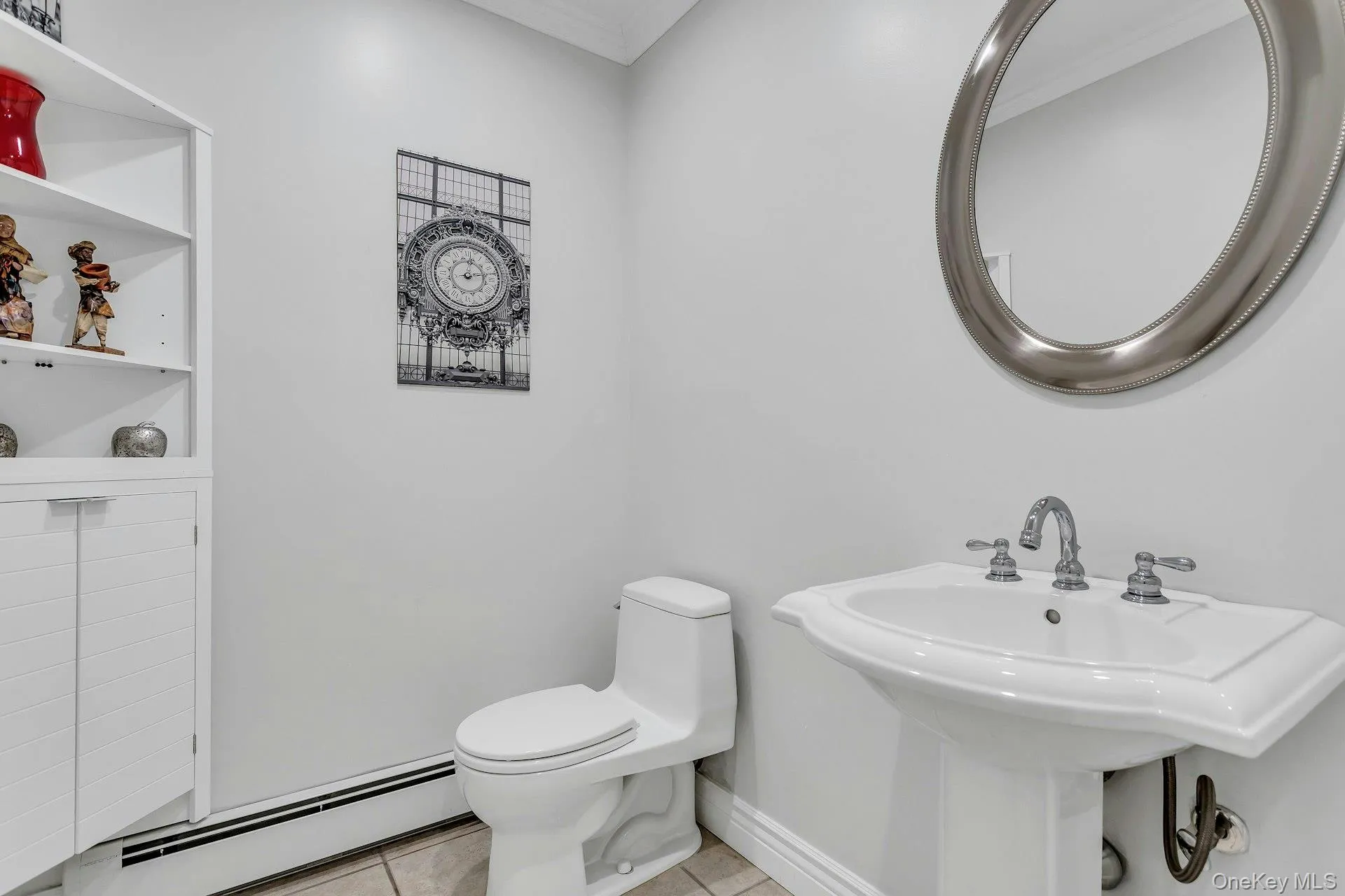 Half bath featuring a baseboard radiator, tile patterned flooring, crown molding, toilet, and a sink Half bath featuring a baseboard radiator, tile patterned flooring, crown molding, toilet, and a sink
