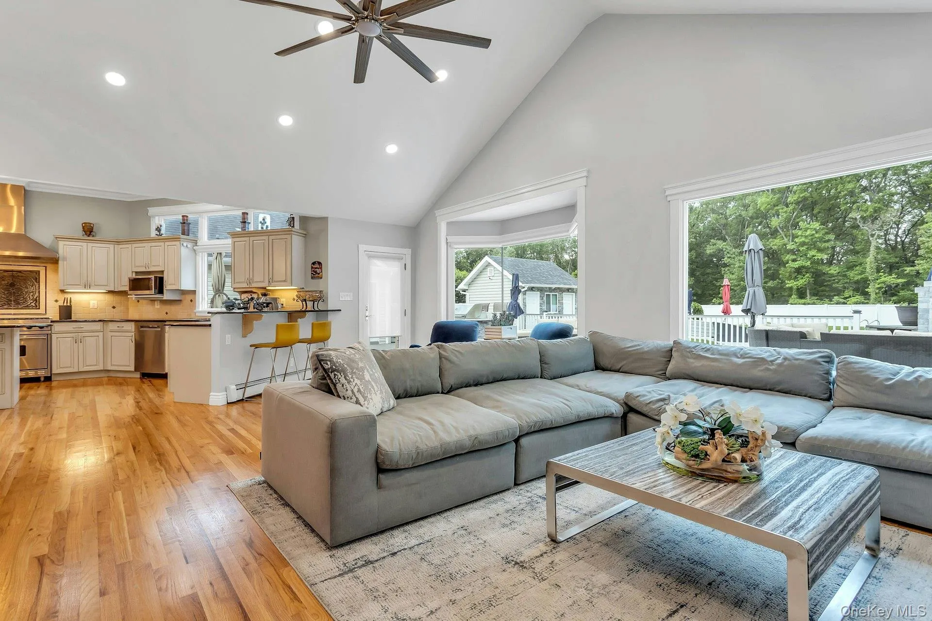 Living area with ceiling fan, high vaulted ceiling, light wood finished floors, and recessed lighting Living area with ceiling fan, high vaulted ceiling, light wood finished floors, and recessed lighting