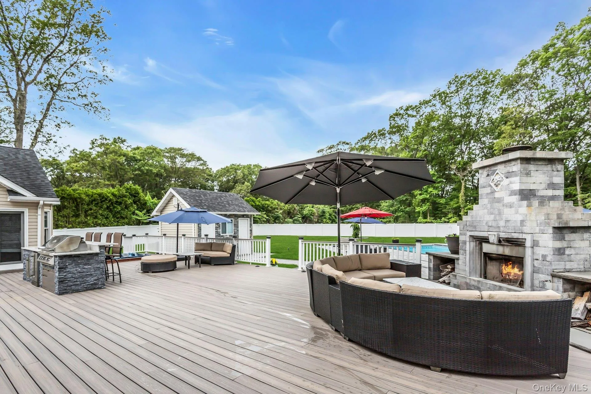 Wooden terrace with an outdoor living space with a fireplace and a fenced backyard Wooden terrace with an outdoor living space with a fireplace and a fenced backyard