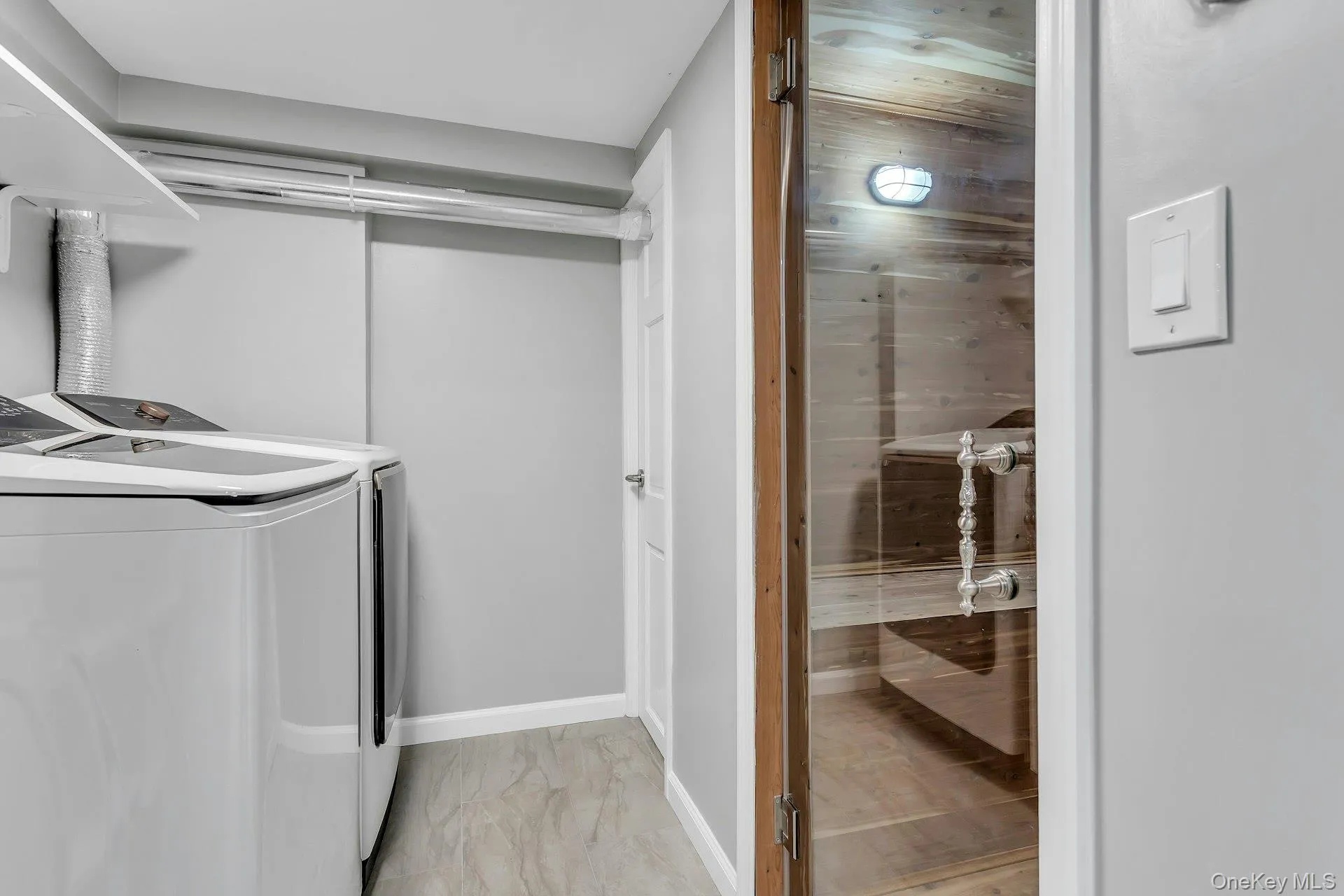 Laundry area featuring washer and clothes dryer, light marble finish flooring, and baseboards Laundry area featuring washer and clothes dryer, light marble finish flooring, and baseboards