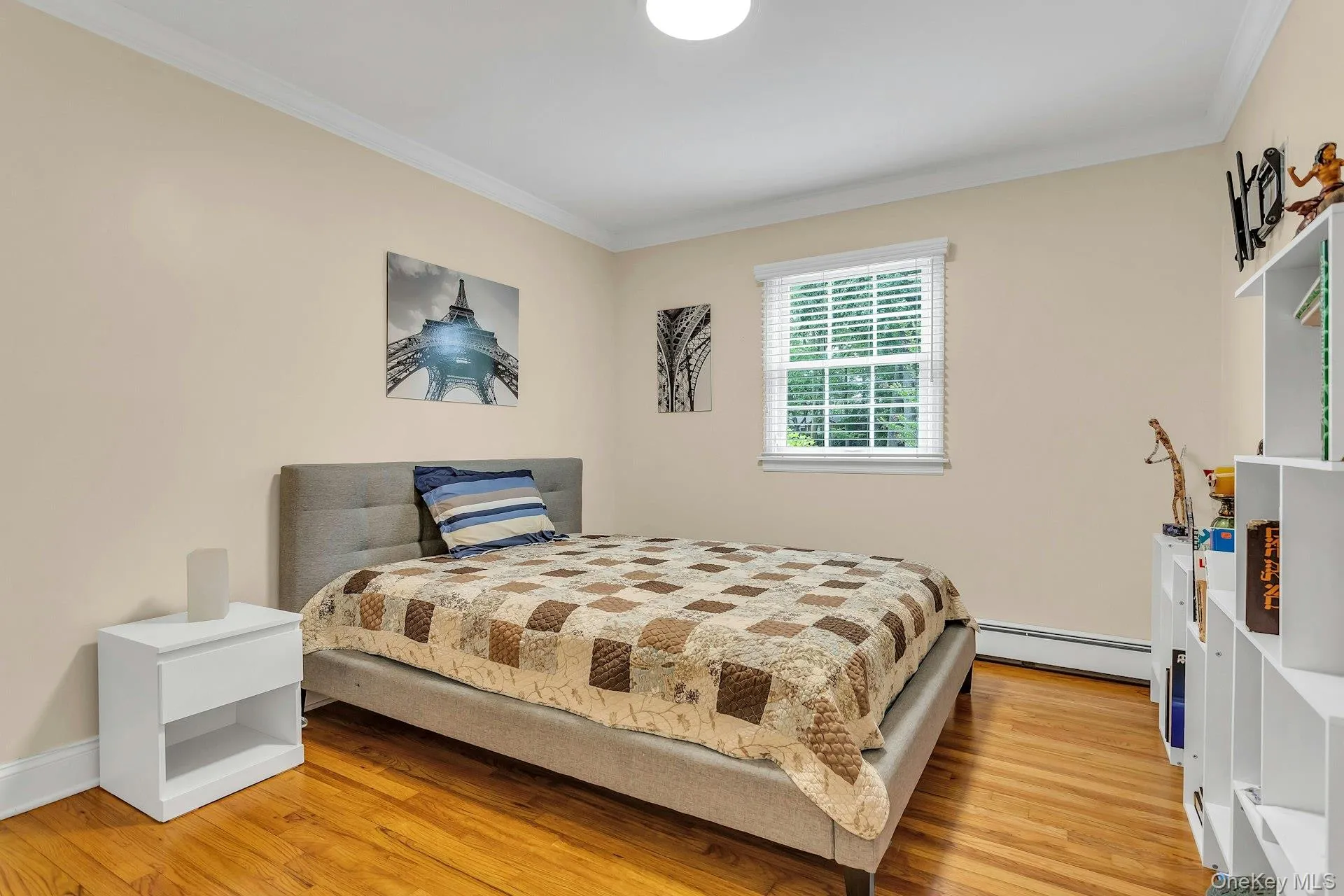 Bedroom with baseboard heating, ornamental molding, and light wood finished floors Bedroom with baseboard heating, ornamental molding, and light wood finished floors