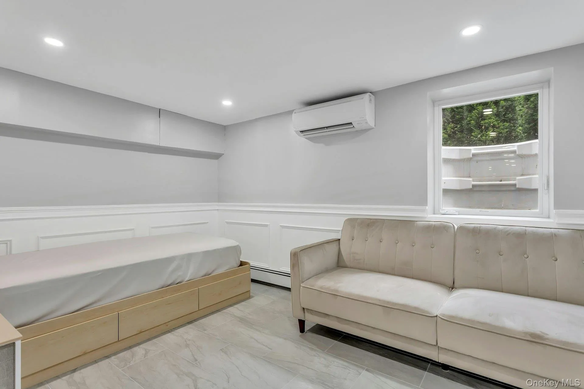Living area featuring a wall mounted AC, a wainscoted wall, recessed lighting, light marble finish floors, and a baseboard radiator Living area featuring a wall mounted AC, a wainscoted wall, recessed lighting, light marble finish floors, and a baseboard radiator