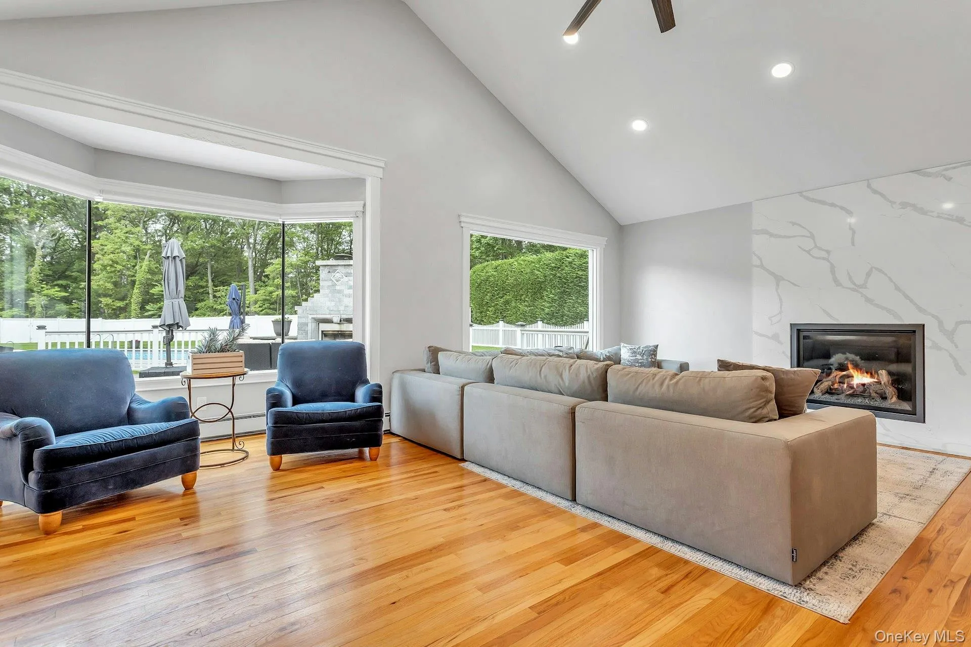 Living room featuring light wood-style floors, high vaulted ceiling, a fireplace, a ceiling fan, and recessed lighting Living room featuring light wood-style floors, high vaulted ceiling, a fireplace, a ceiling fan, and recessed lighting