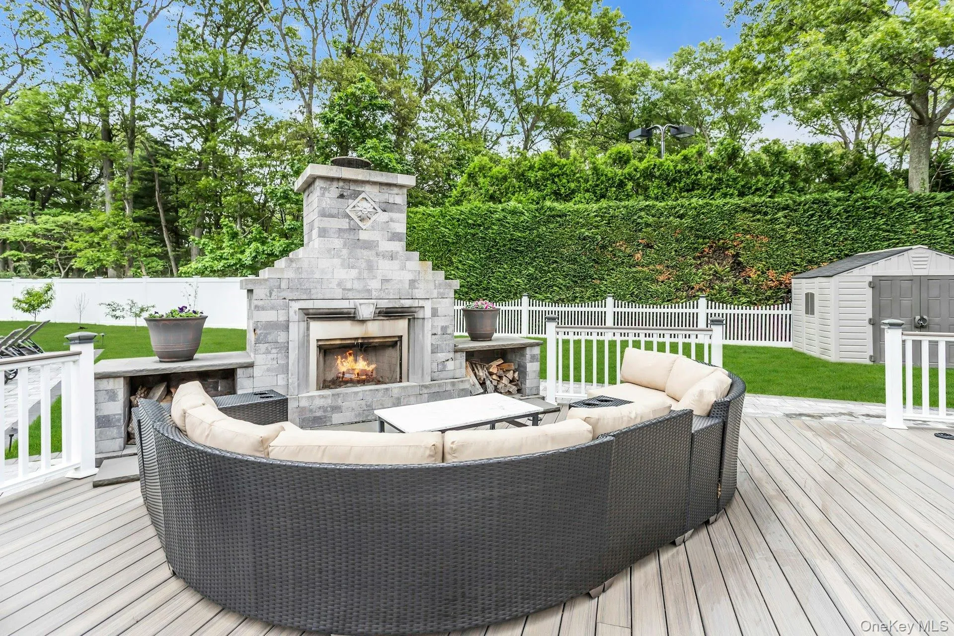 Wooden terrace featuring an outdoor living space with a fireplace and view of wooded area Wooden terrace featuring an outdoor living space with a fireplace and view of wooded area