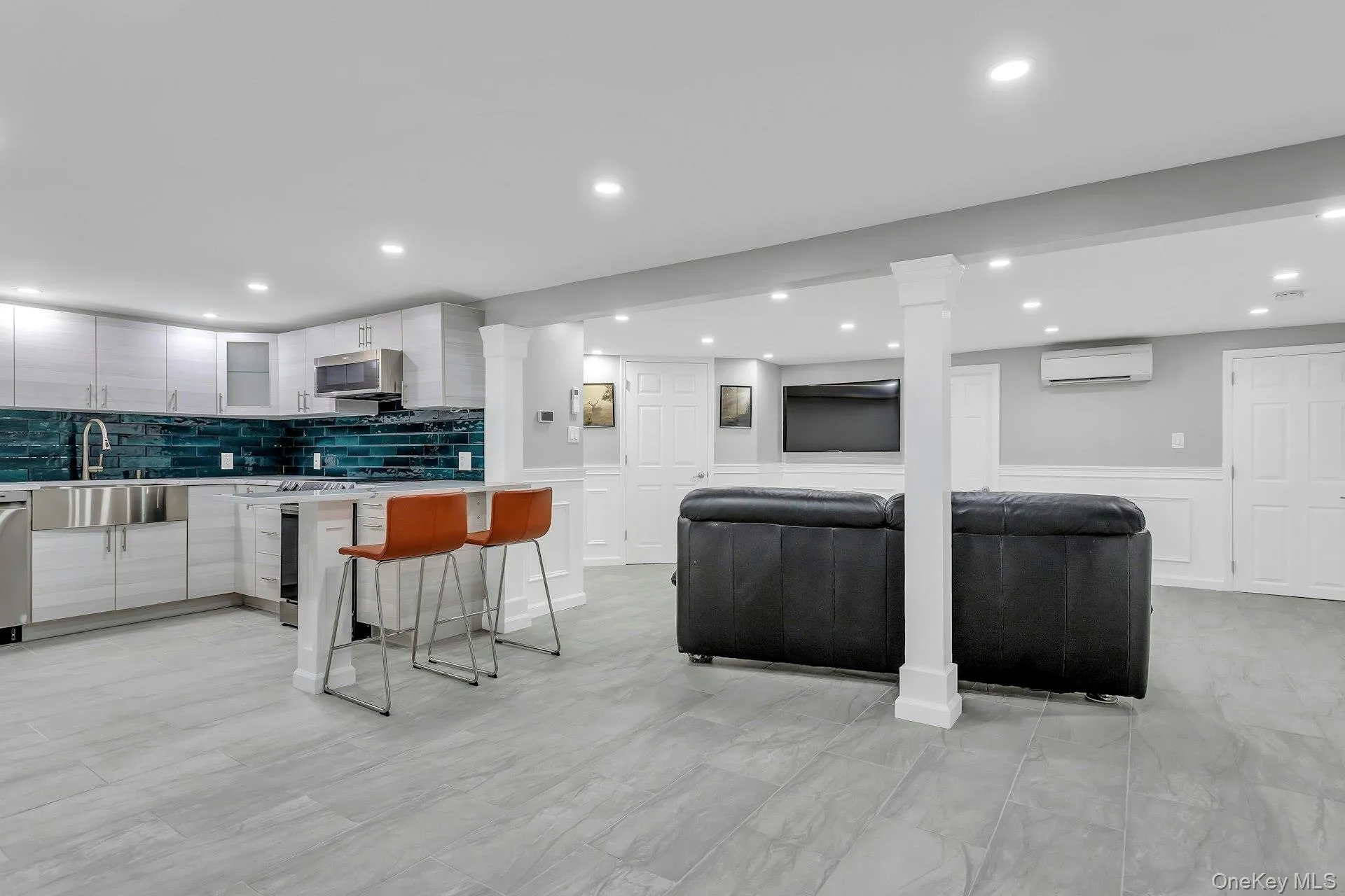 Kitchen with a sink, modern cabinets, an AC wall unit, stainless steel appliances, and a wainscoted wall Kitchen with a sink, modern cabinets, an AC wall unit, stainless steel appliances, and a wainscoted wall