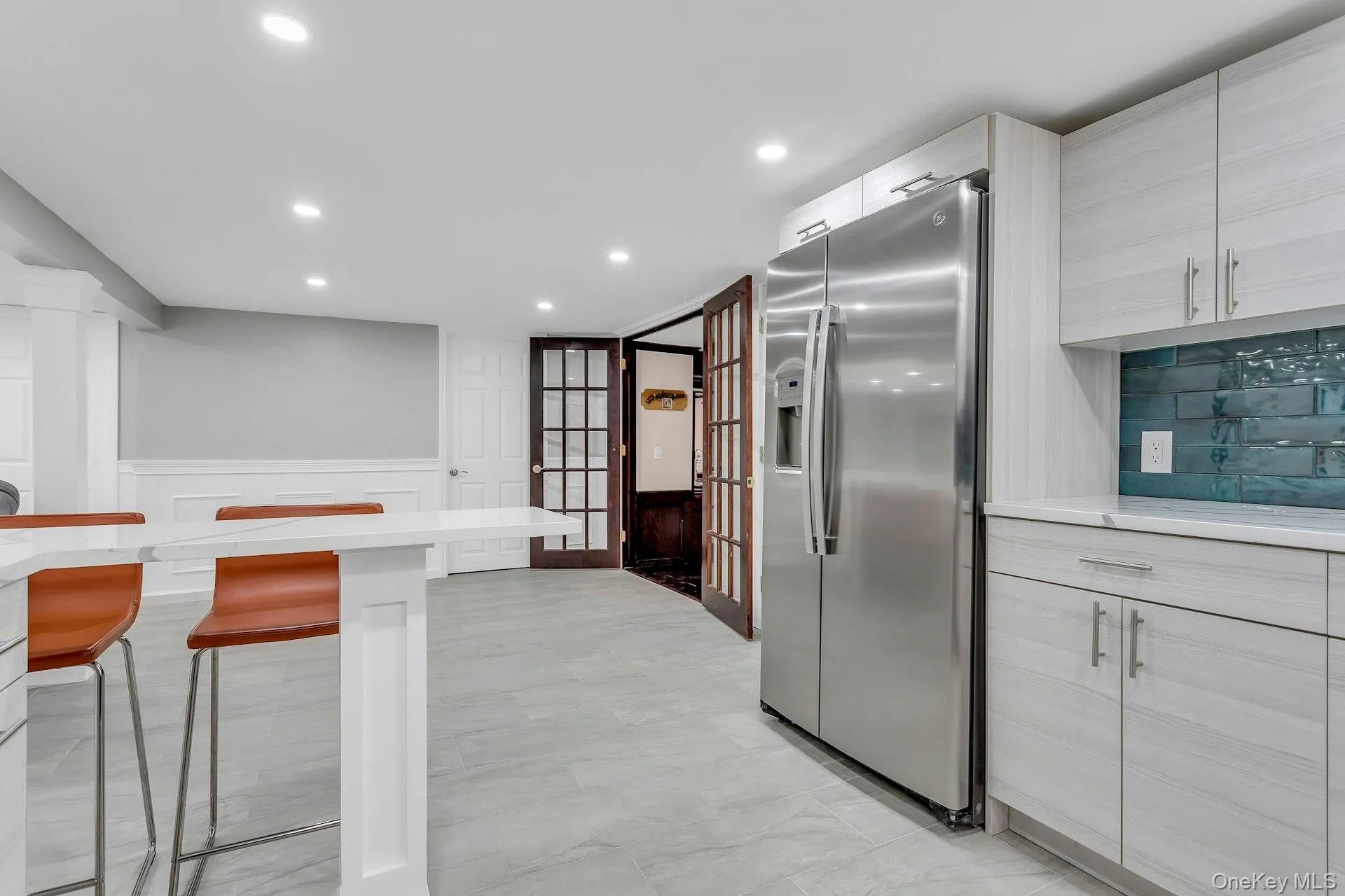 Kitchen with stainless steel refrigerator with ice dispenser, a breakfast bar, recessed lighting, wainscoting, and light marble finish flooring Kitchen with stainless steel refrigerator with ice dispenser, a breakfast bar, recessed lighting, wainscoting, and light marble finish flooring