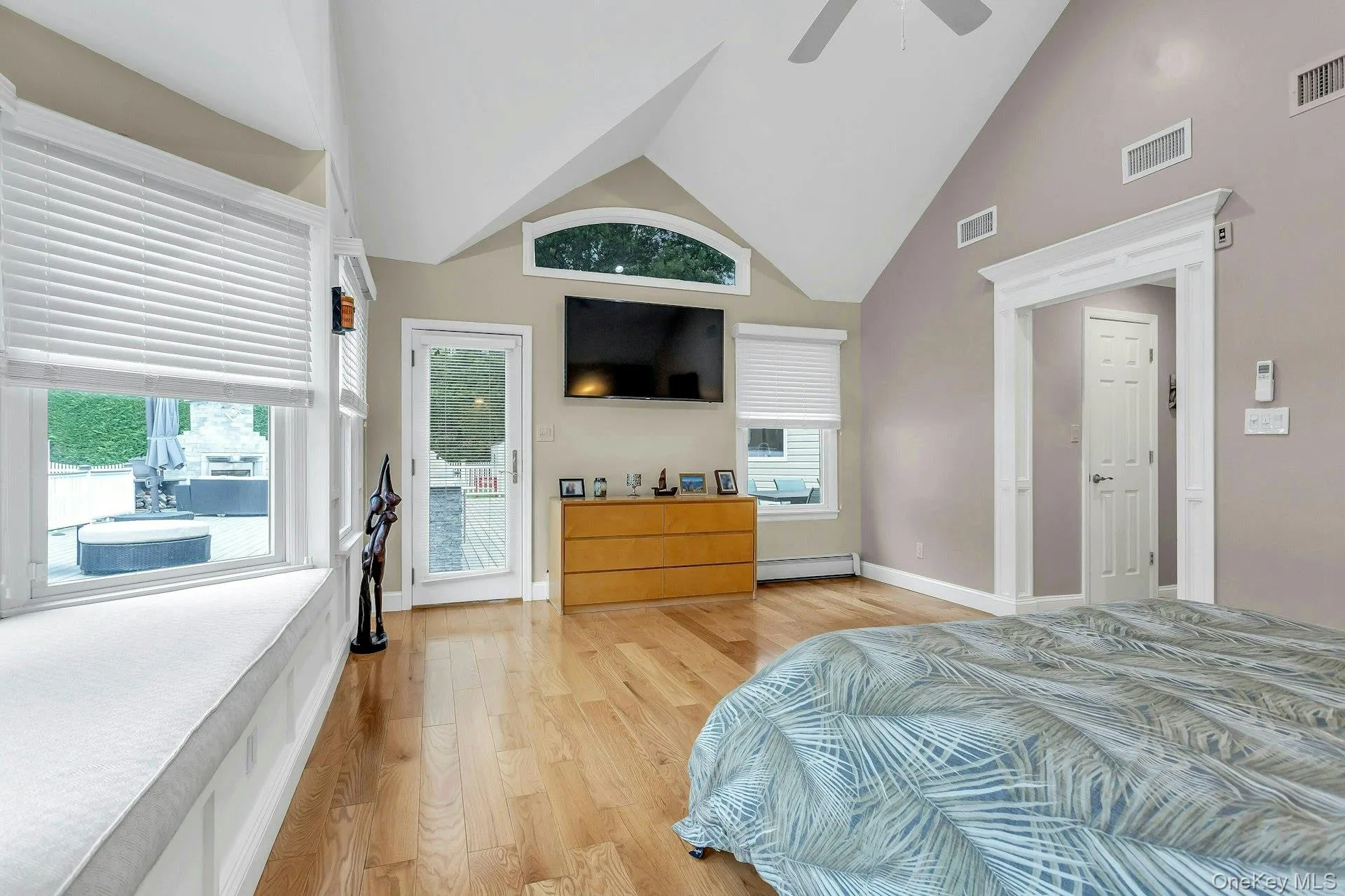 Bedroom with light wood-style flooring, a baseboard radiator, a ceiling fan, baseboards, and high vaulted ceiling Bedroom with light wood-style flooring, a baseboard radiator, a ceiling fan, baseboards, and high vaulted ceiling
