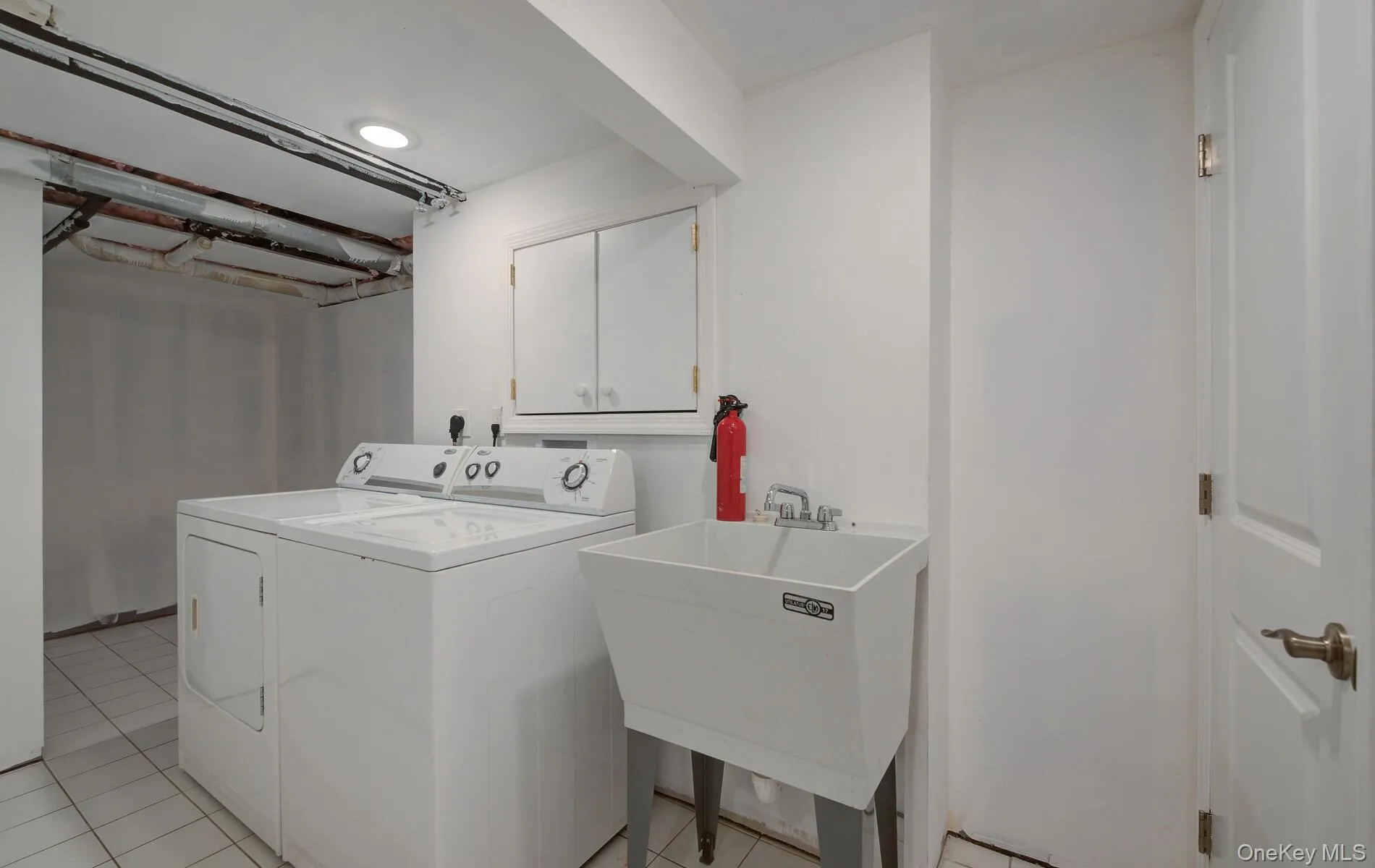 Laundry area with washer and clothes dryer, cabinet space, and light tile patterned floors Laundry area with washer and clothes dryer, cabinet space, and light tile patterned floors