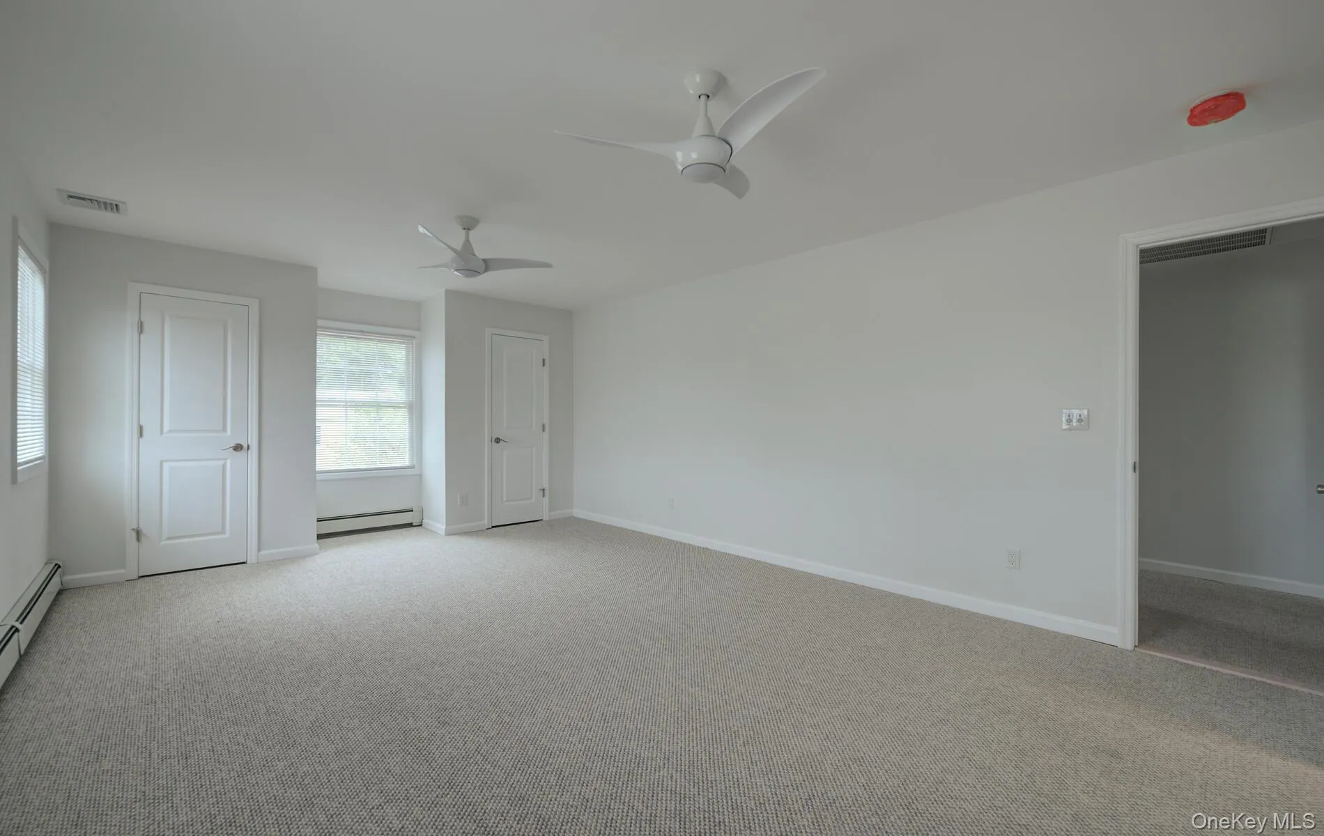 Empty room with a baseboard heating unit, a ceiling fan, light carpet, and baseboards Empty room with a baseboard heating unit, a ceiling fan, light carpet, and baseboards