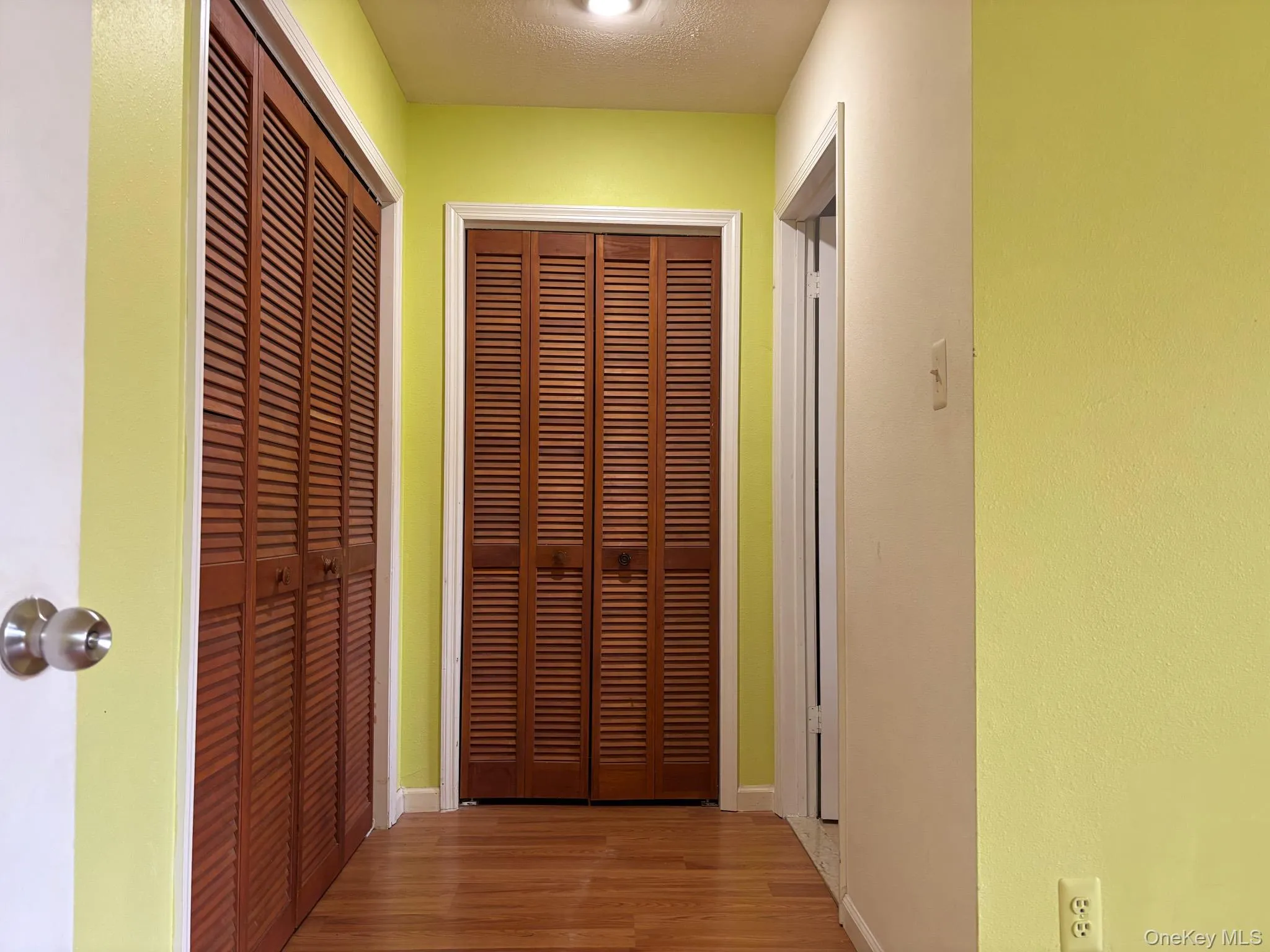 Hallway featuring wood finished floors and 2 closets Hallway featuring wood finished floors and 2 closets