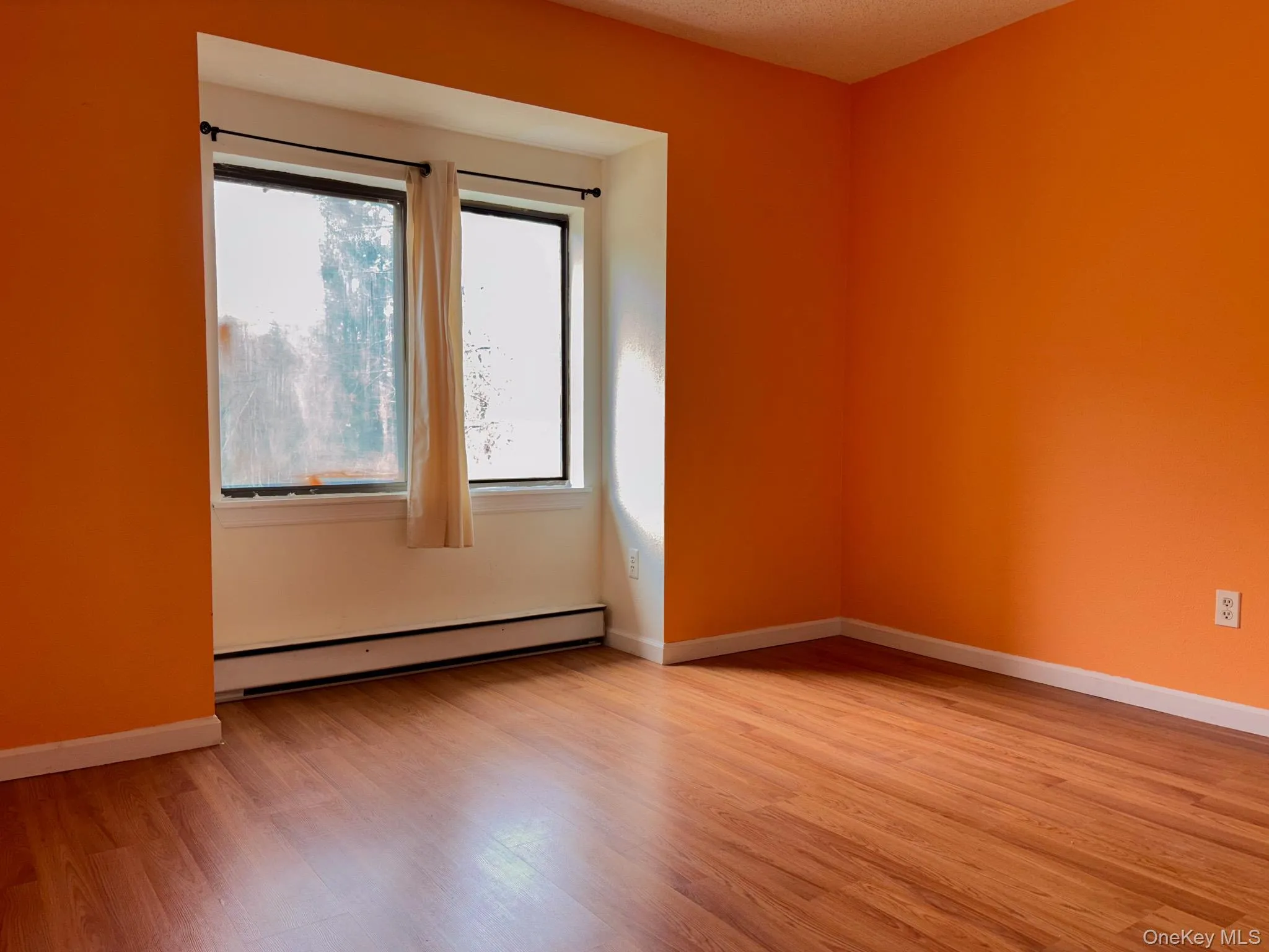 Unfurnished bedroom with baseboard heating and light wood finished floors Unfurnished bedroom with baseboard heating and light wood finished floors