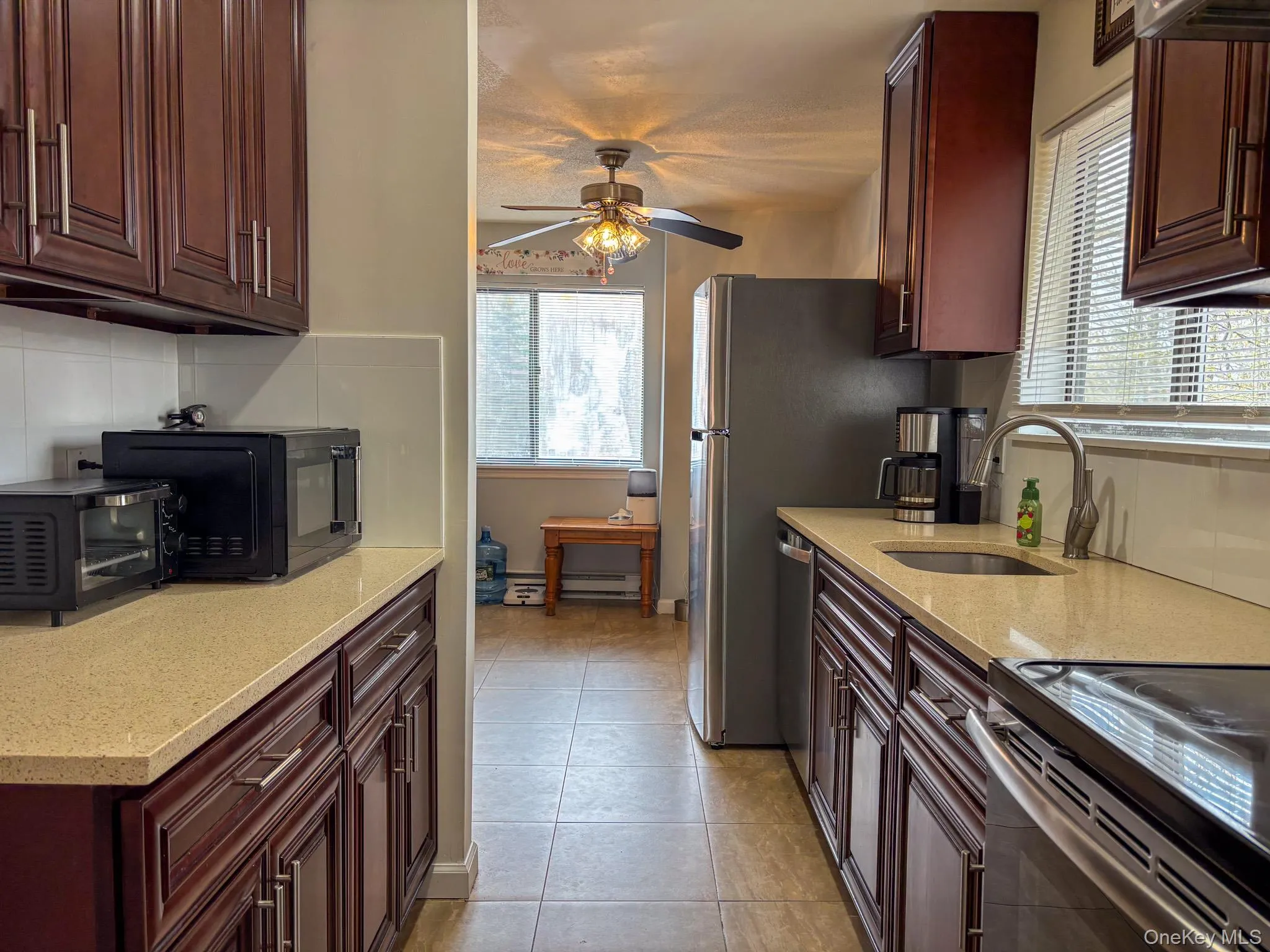 Kitchen with a sink, decorative backsplash, ceiling fan, light tile patterned floors, and healthy amount of natural light Kitchen with a sink, decorative backsplash, ceiling fan, light tile patterned floors, and healthy amount of natural light