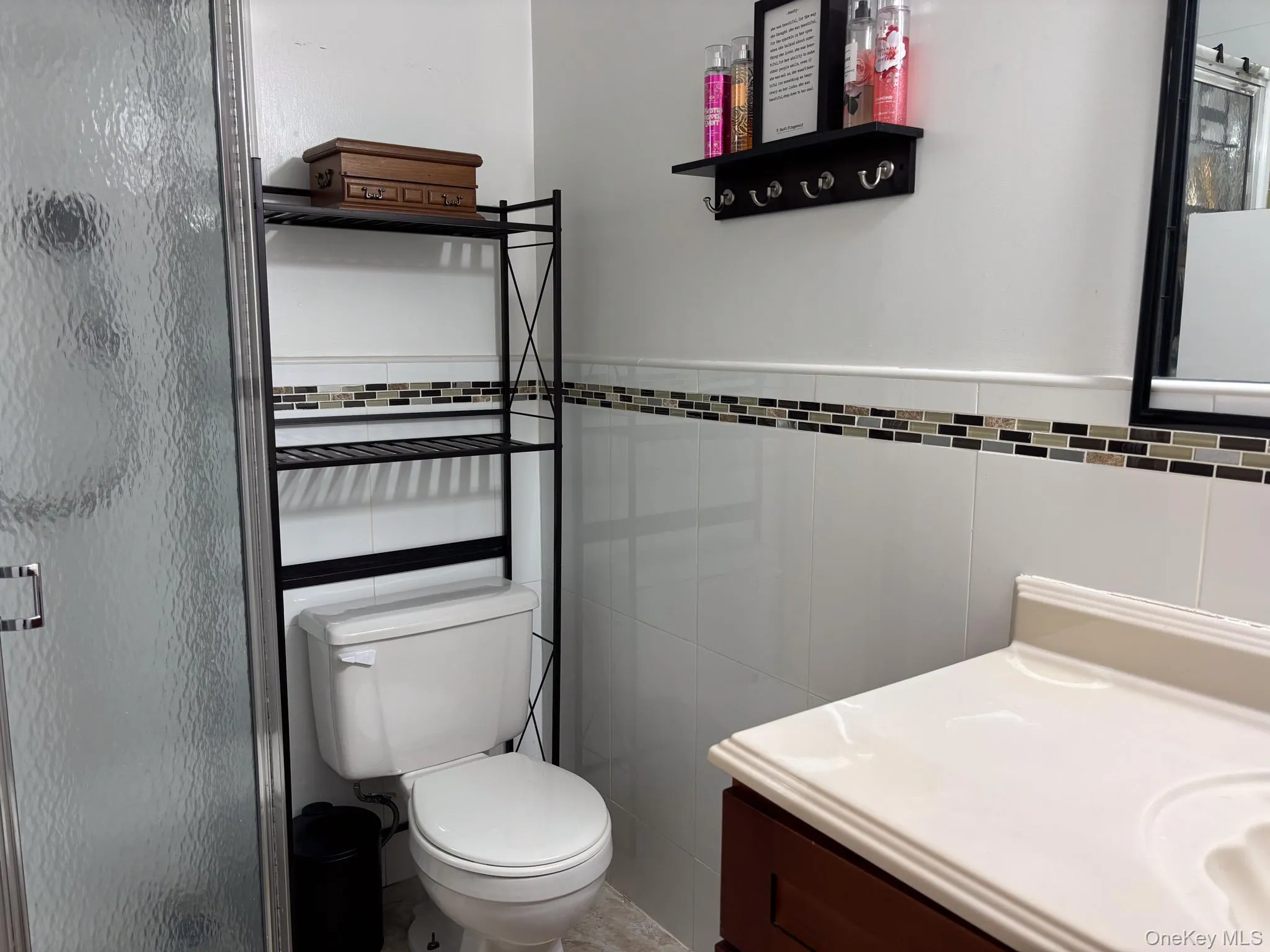 Full bath featuring tile walls, vanity, a shower stall, and toilet Full bath featuring tile walls, vanity, a shower stall, and toilet
