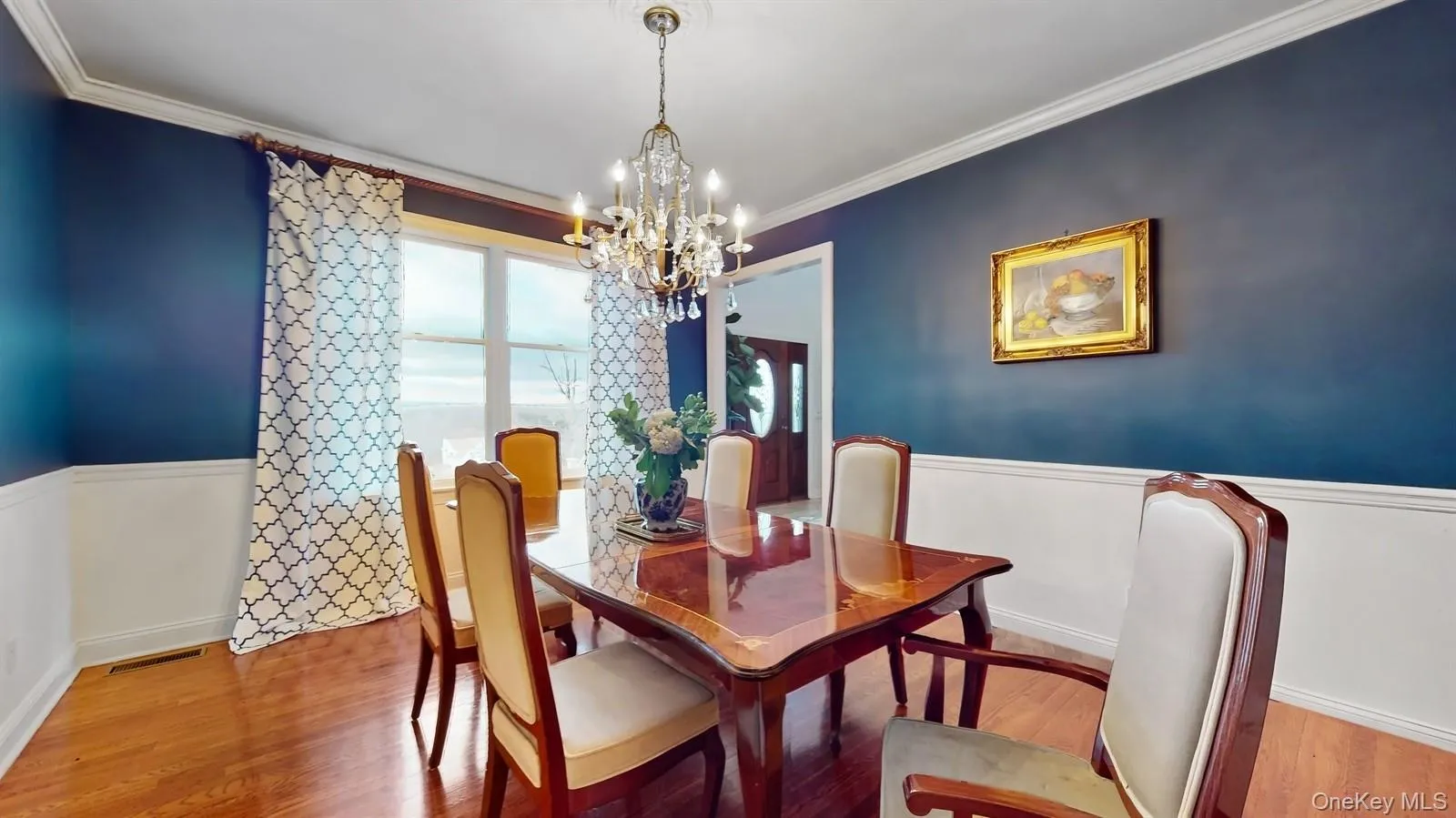 Dining space with a chandelier, wood finished floors, and crown molding Dining space with a chandelier, wood finished floors, and crown molding