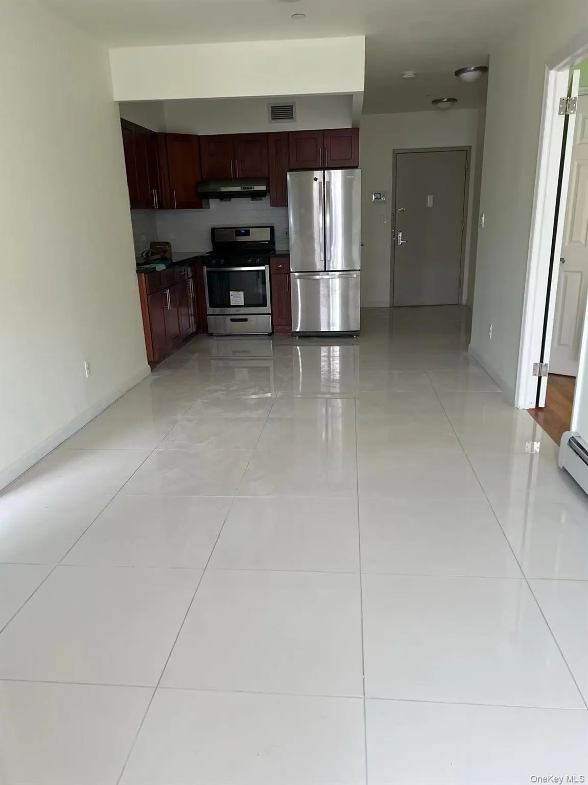 Kitchen with stainless steel appliances, dark brown cabinets, under cabinet range hood, light tile patterned floors, and dark countertops Kitchen with stainless steel appliances, dark brown cabinets, under cabinet range hood, light tile patterned floors, and dark countertops