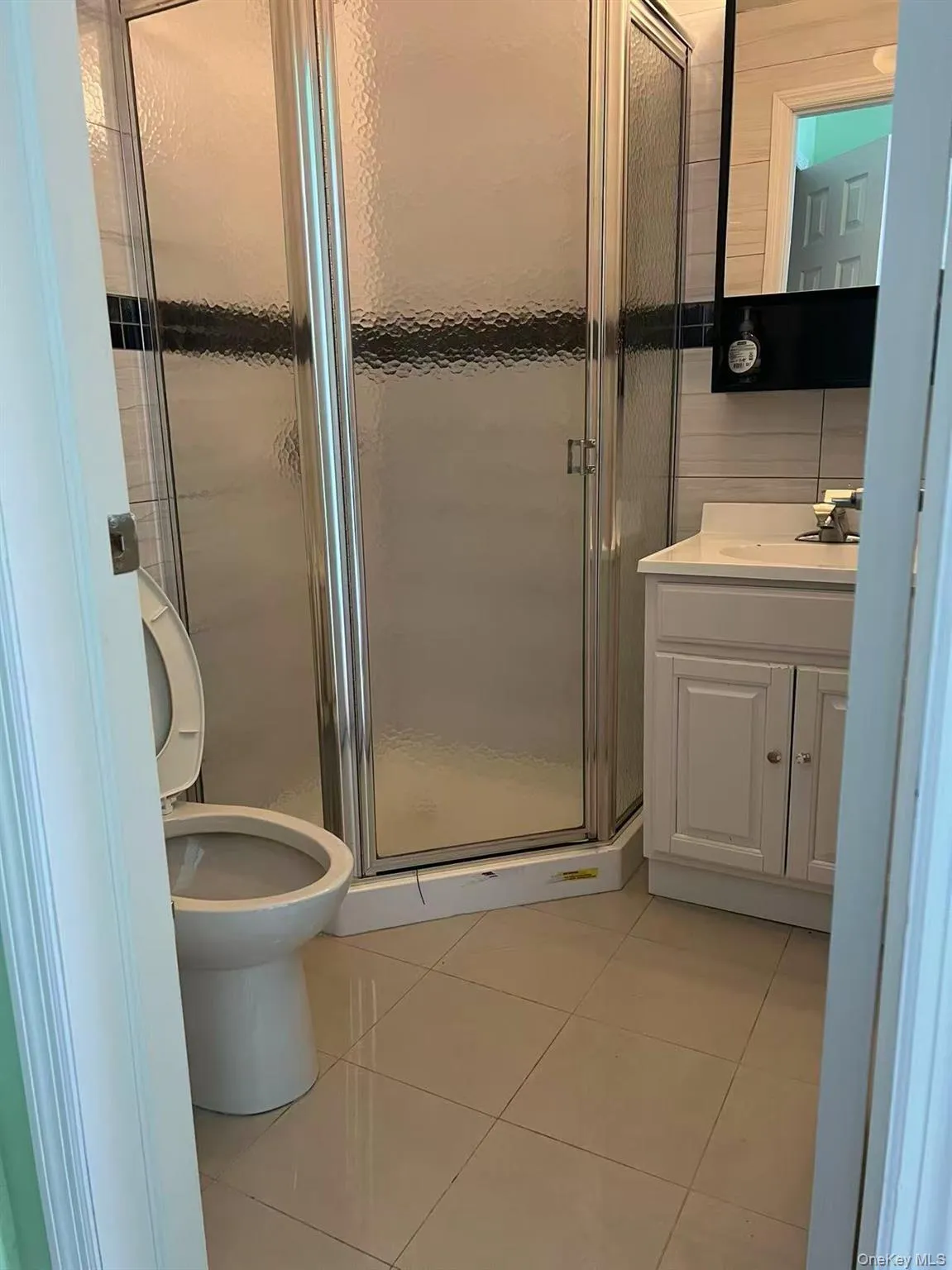 Full bathroom featuring vanity, tile patterned floors, a stall shower, and toilet Full bathroom featuring vanity, tile patterned floors, a stall shower, and toilet