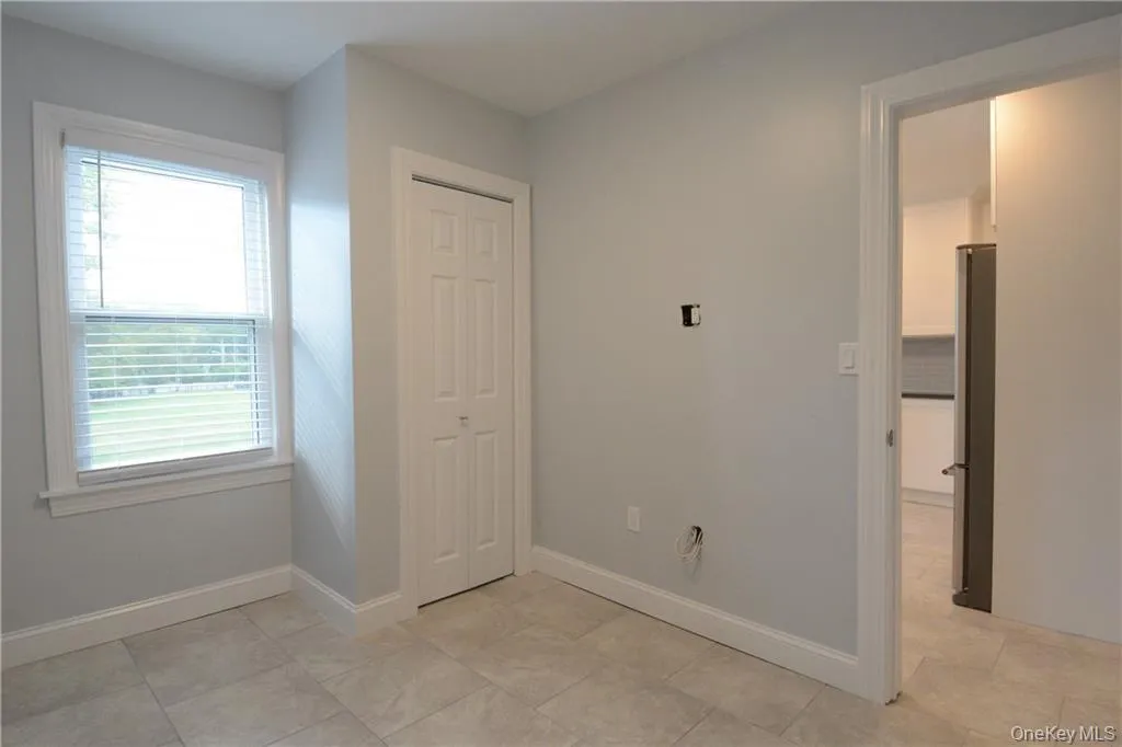 Unfurnished bedroom with baseboards, a closet, and freestanding refrigerator Unfurnished bedroom with baseboards, a closet, and freestanding refrigerator