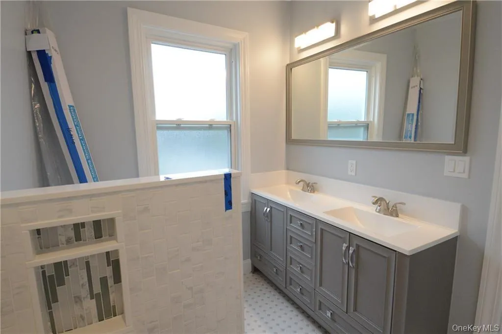 Full bath featuring plenty of natural light, double vanity, and tile patterned floors Full bath featuring plenty of natural light, double vanity, and tile patterned floors
