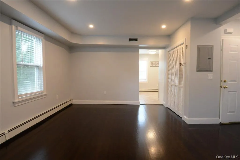 Unfurnished room with electric panel, a baseboard radiator, baseboards, wood finished floors, and baseboard heating Unfurnished room with electric panel, a baseboard radiator, baseboards, wood finished floors, and baseboard heating