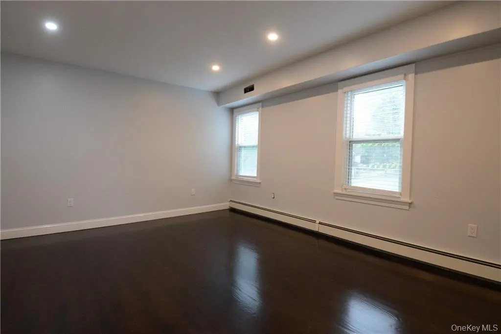 Spare room with baseboard heating, recessed lighting, dark wood-style floors, and baseboards Spare room with baseboard heating, recessed lighting, dark wood-style floors, and baseboards