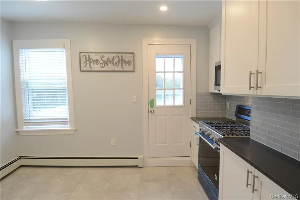 Kitchen with stainless steel appliances, dark countertops, backsplash, white cabinetry, and recessed lighting Kitchen with stainless steel appliances, dark countertops, backsplash, white cabinetry, and recessed lighting