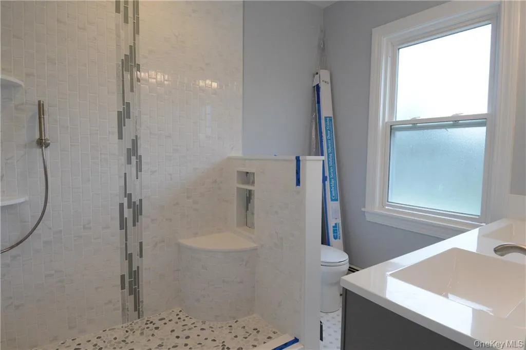 Bathroom featuring a stall shower, vanity, and toilet Bathroom featuring a stall shower, vanity, and toilet