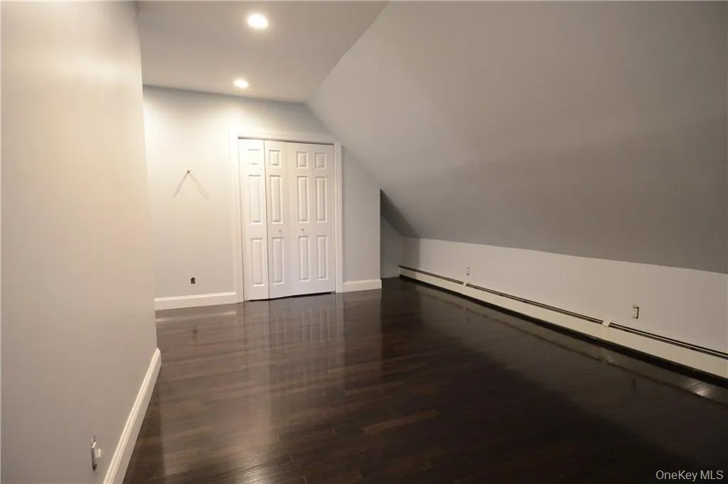 Bonus room with baseboards, lofted ceiling, baseboard heating, wood finished floors, and recessed lighting Bonus room with baseboards, lofted ceiling, baseboard heating, wood finished floors, and recessed lighting