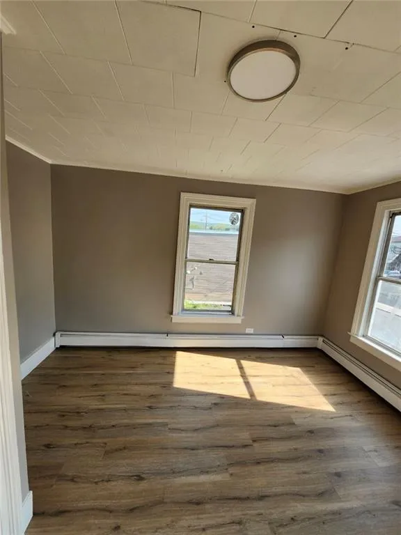 Spare room featuring dark wood-style flooring and baseboards Spare room featuring dark wood-style flooring and baseboards