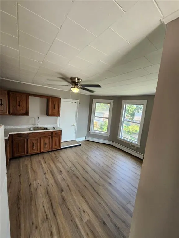 Kitchen with a sink, light wood-style floors, light countertops, ceiling fan, and brown cabinets Kitchen with a sink, light wood-style floors, light countertops, ceiling fan, and brown cabinets