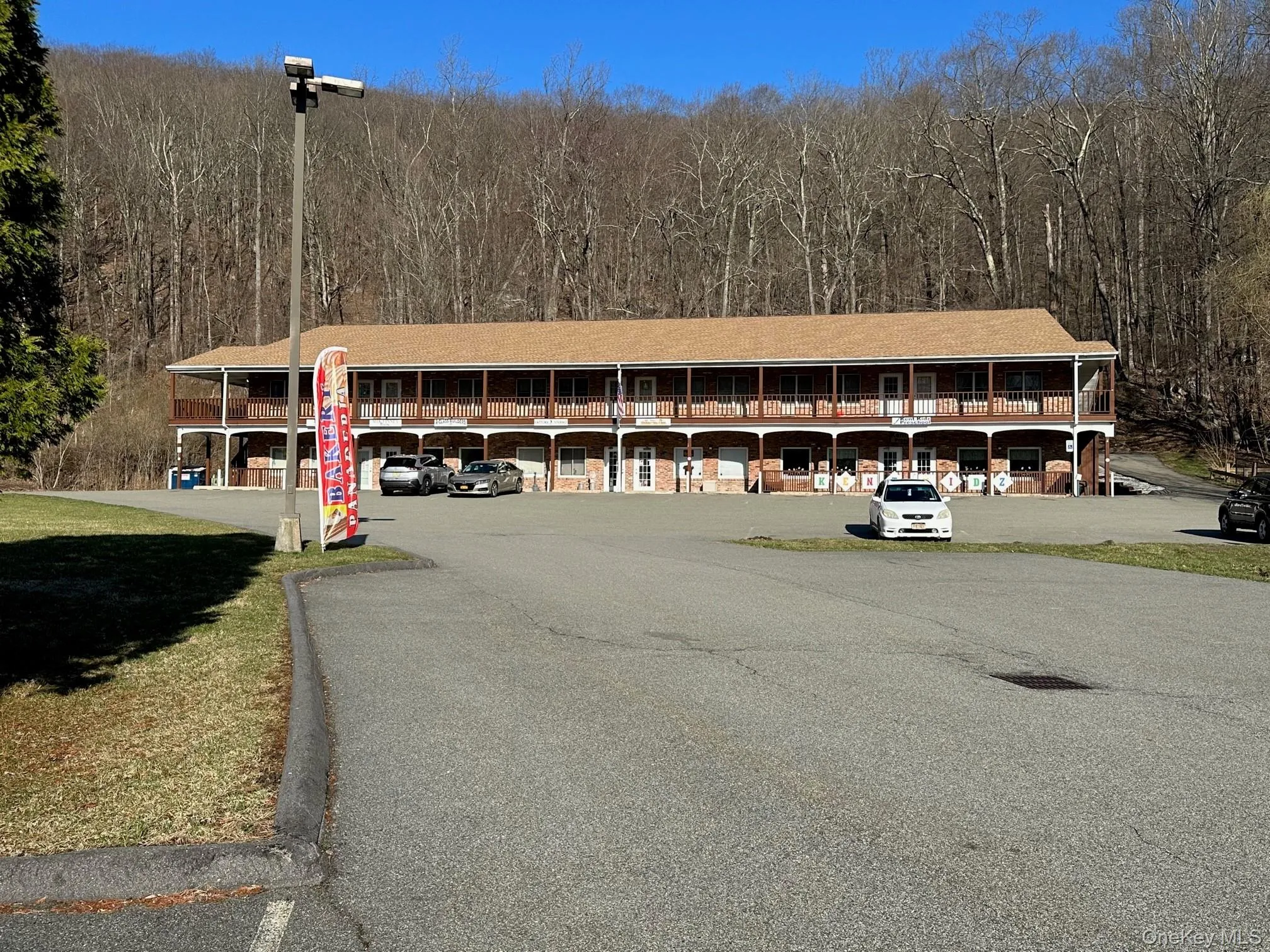 View of property featuring uncovered parking and a wooded view View of property featuring uncovered parking and a wooded view