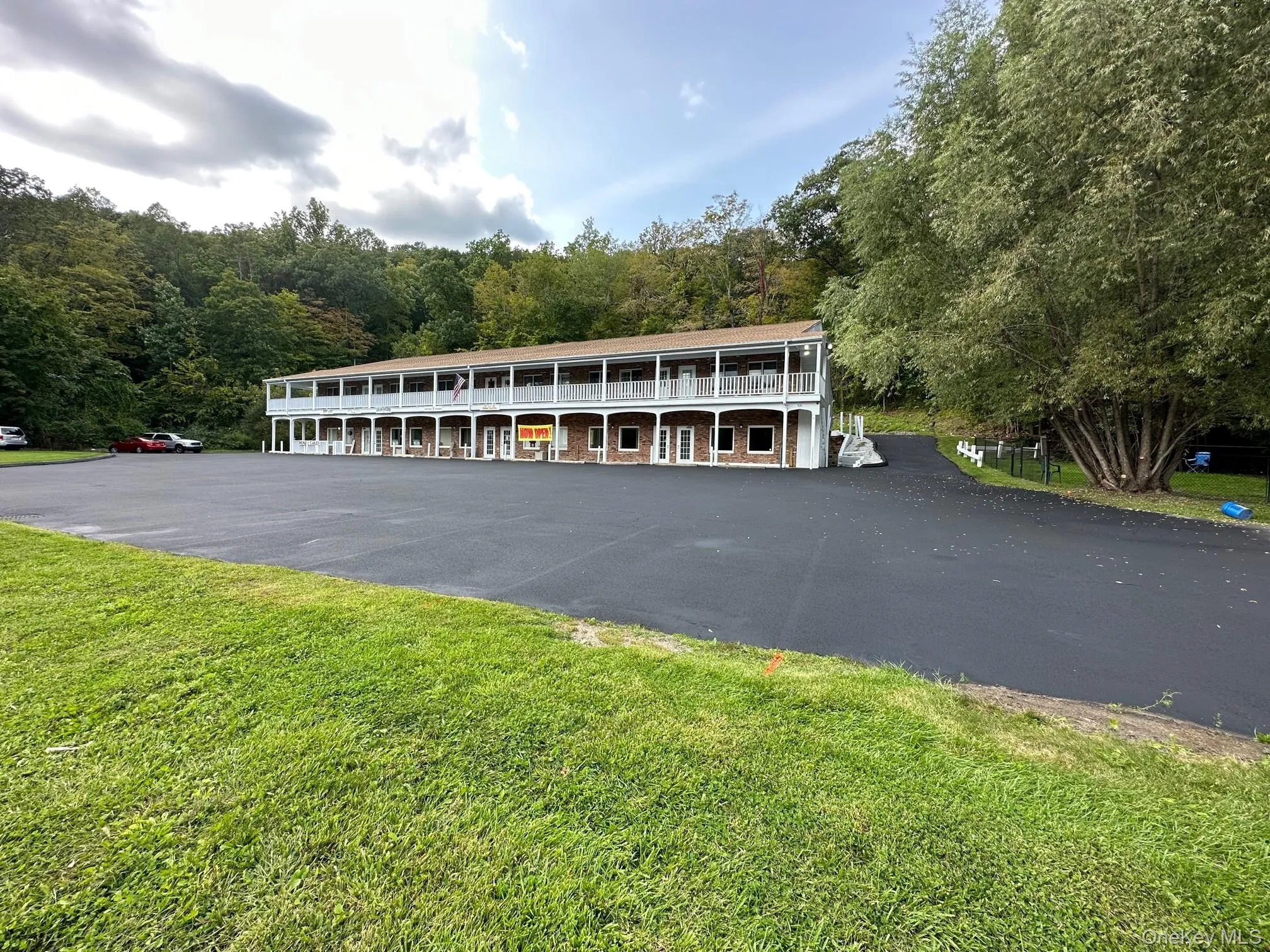 View of front of house featuring uncovered parking, a front lawn, and a forest view View of front of house featuring uncovered parking, a front lawn, and a forest view