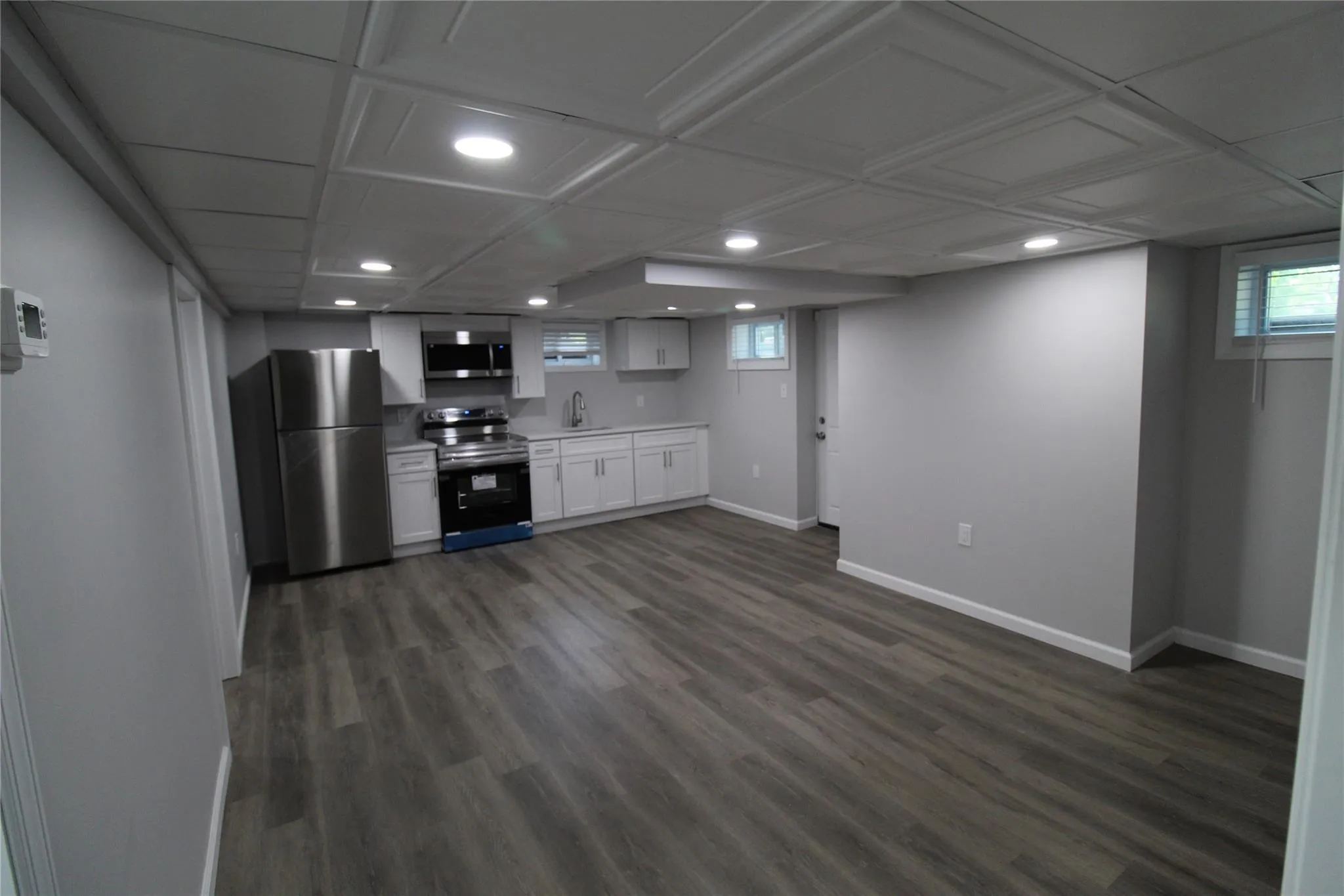 Kitchen with appliances with stainless steel finishes, a sink, baseboards, recessed lighting, and white cabinets Kitchen with appliances with stainless steel finishes, a sink, baseboards, recessed lighting, and white cabinets