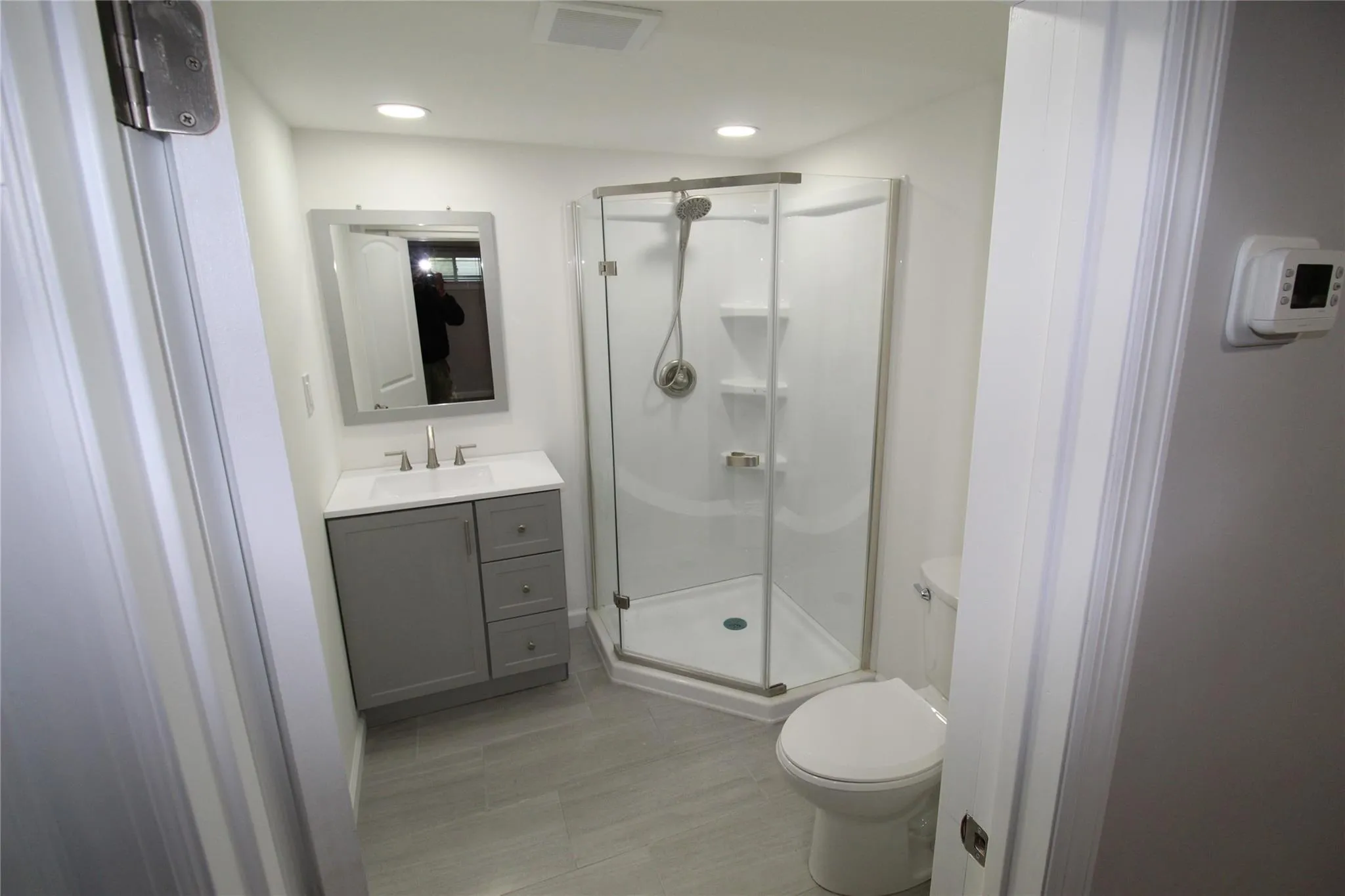Bathroom with a stall shower, toilet, vanity, tile patterned floors, and recessed lighting Bathroom with a stall shower, toilet, vanity, tile patterned floors, and recessed lighting